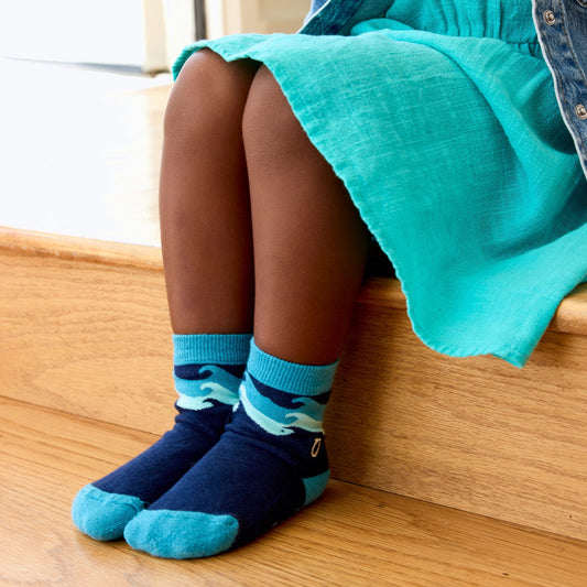 Person wearing blue socks with wave design sitting on a wooden bench.