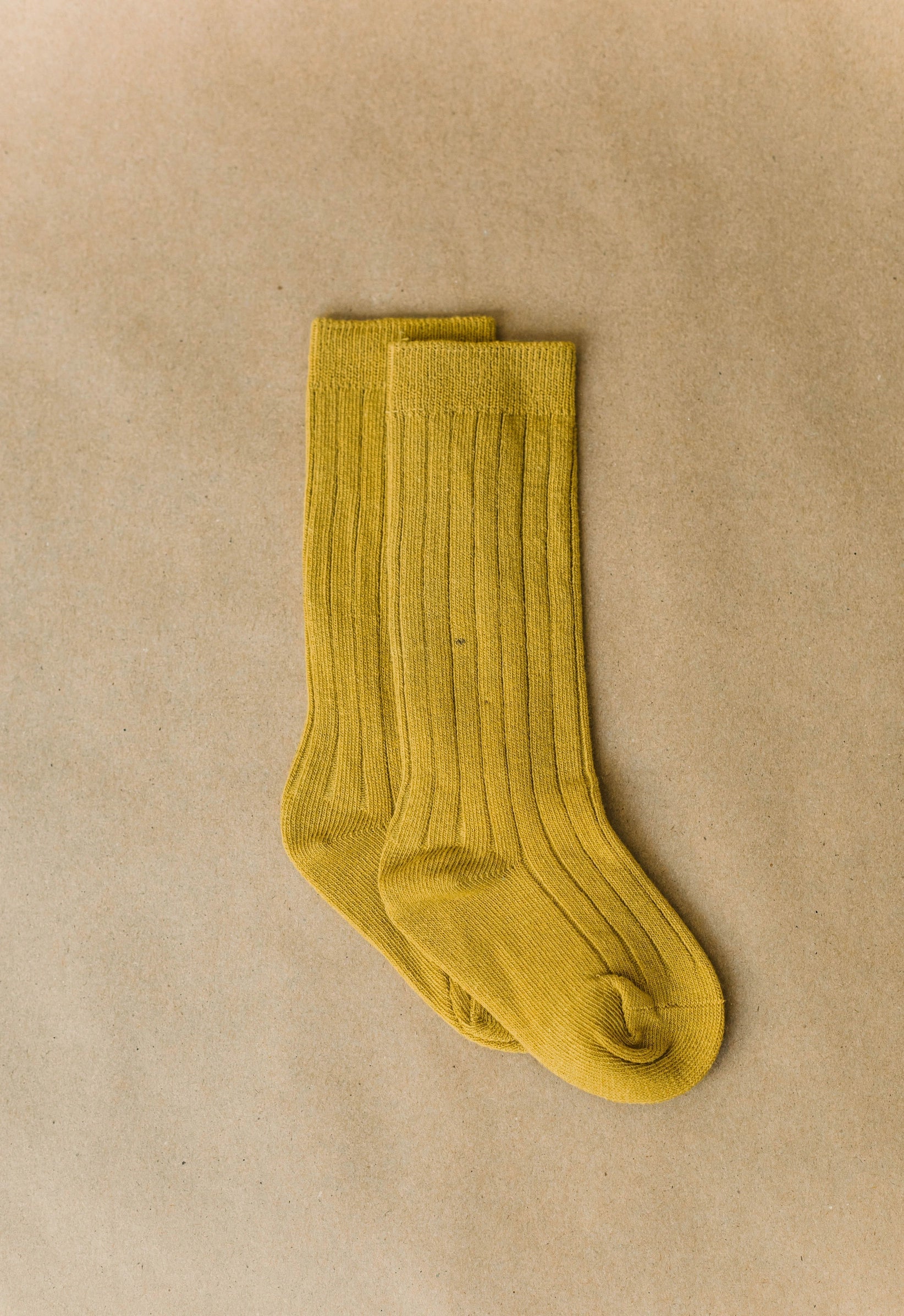 Pair of mustard yellow socks on a beige background