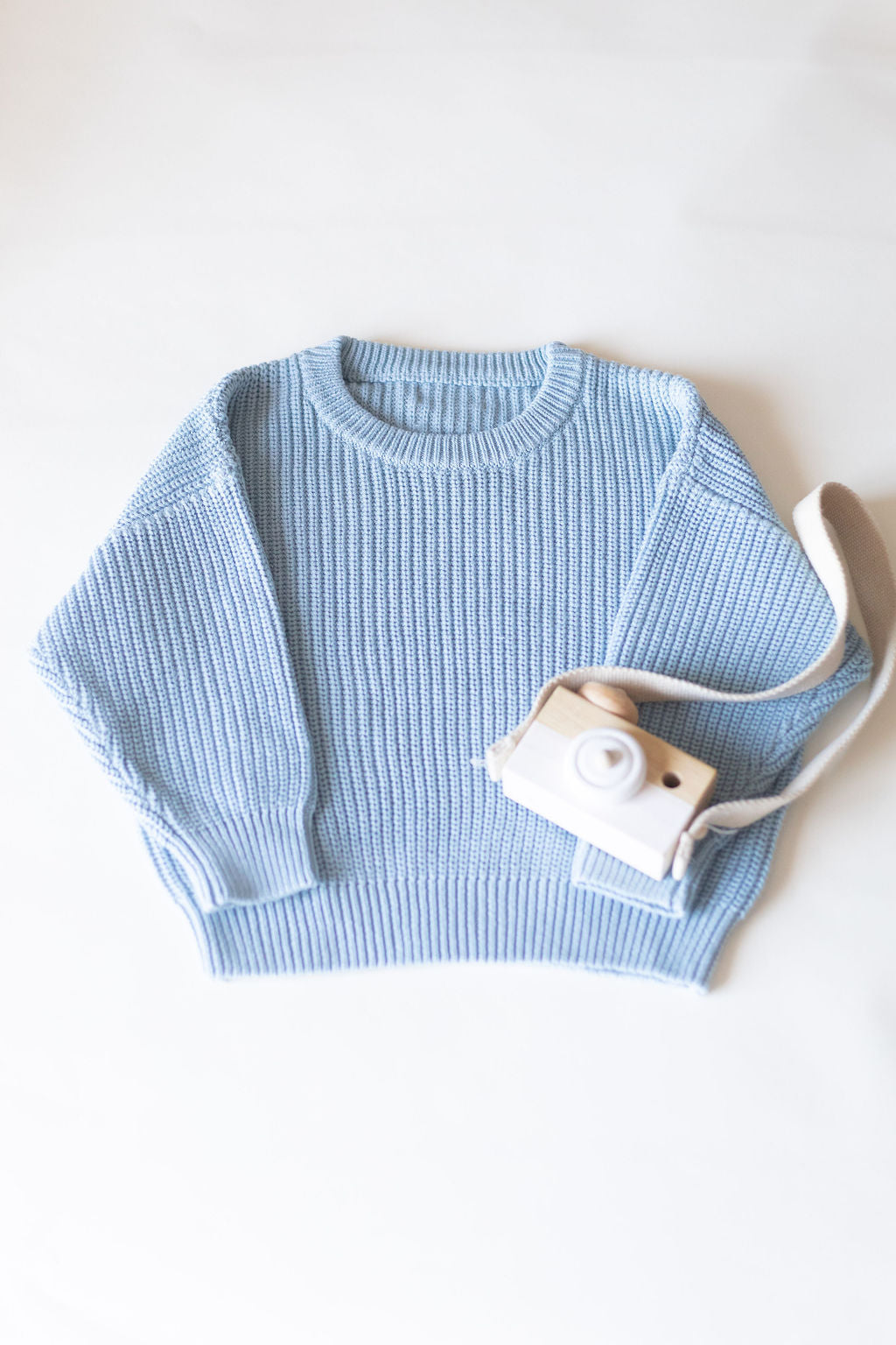 Light blue sweater with a camera on a white background