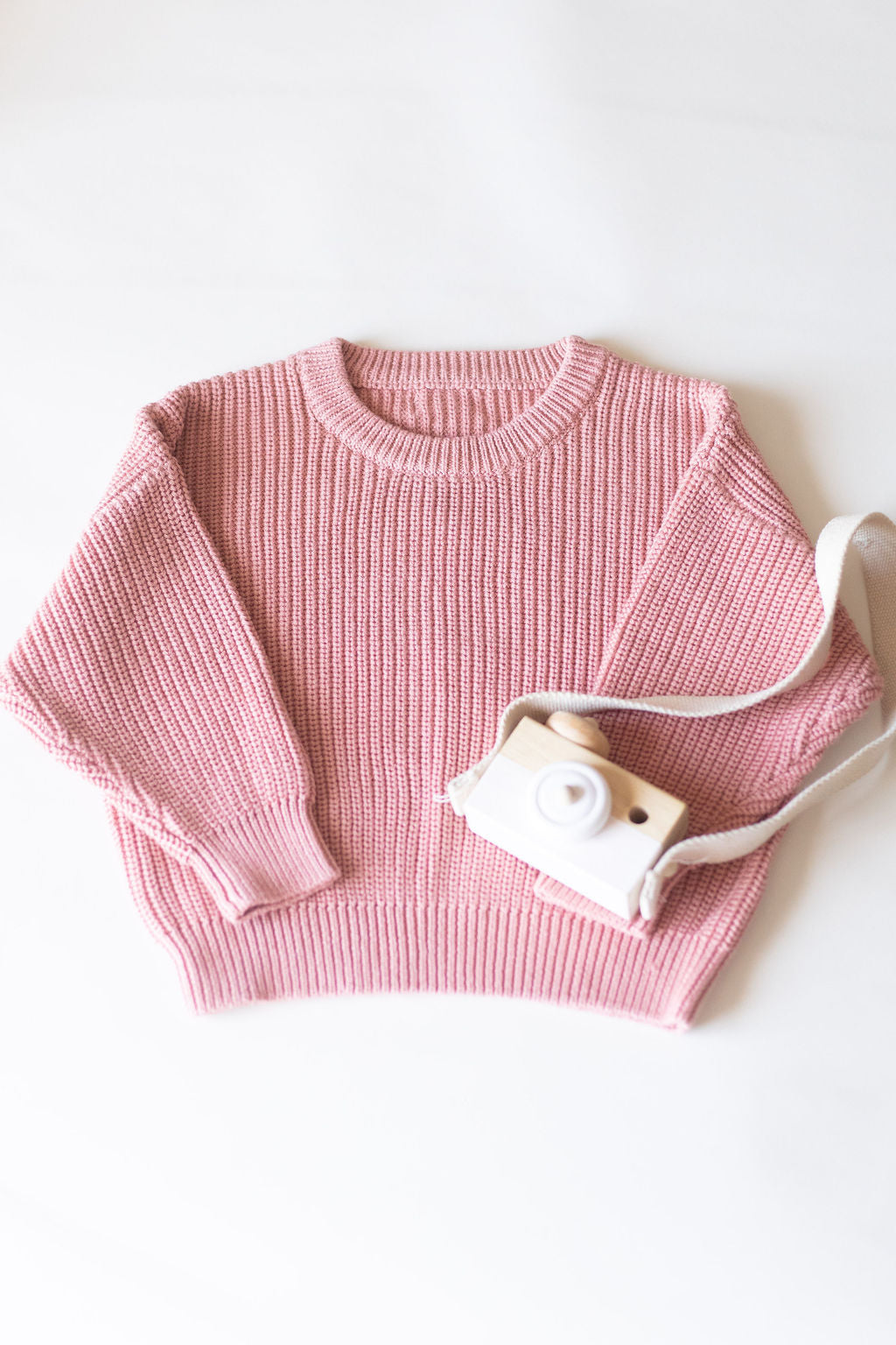 Pink knitted sweater with a small white bag on a light background