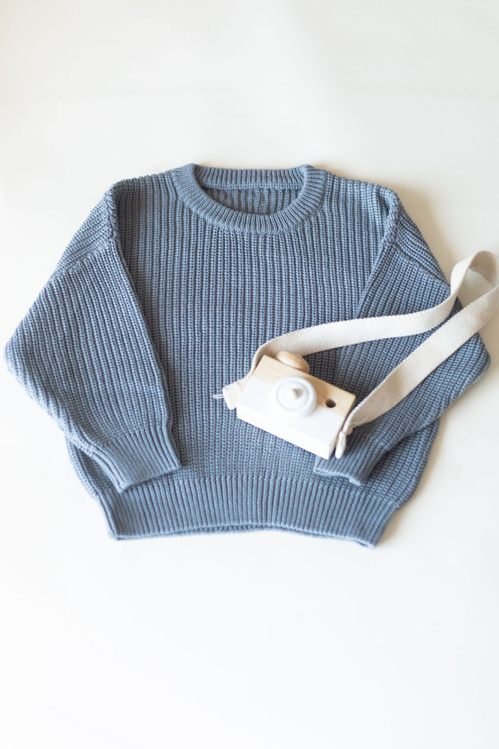 Blue knitted sweater with a white strap on a white background