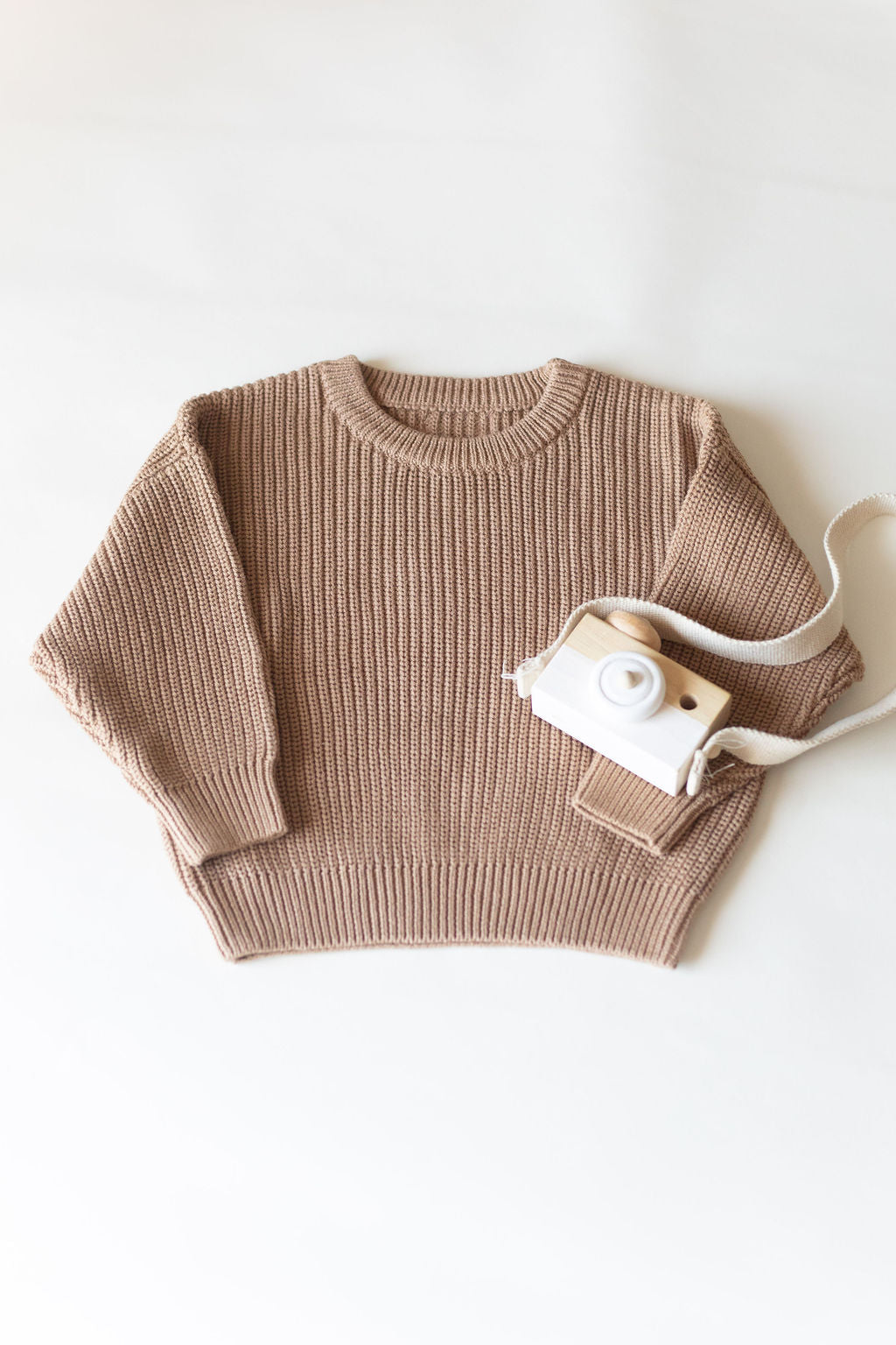 Brown sweater with a white camera on a light background