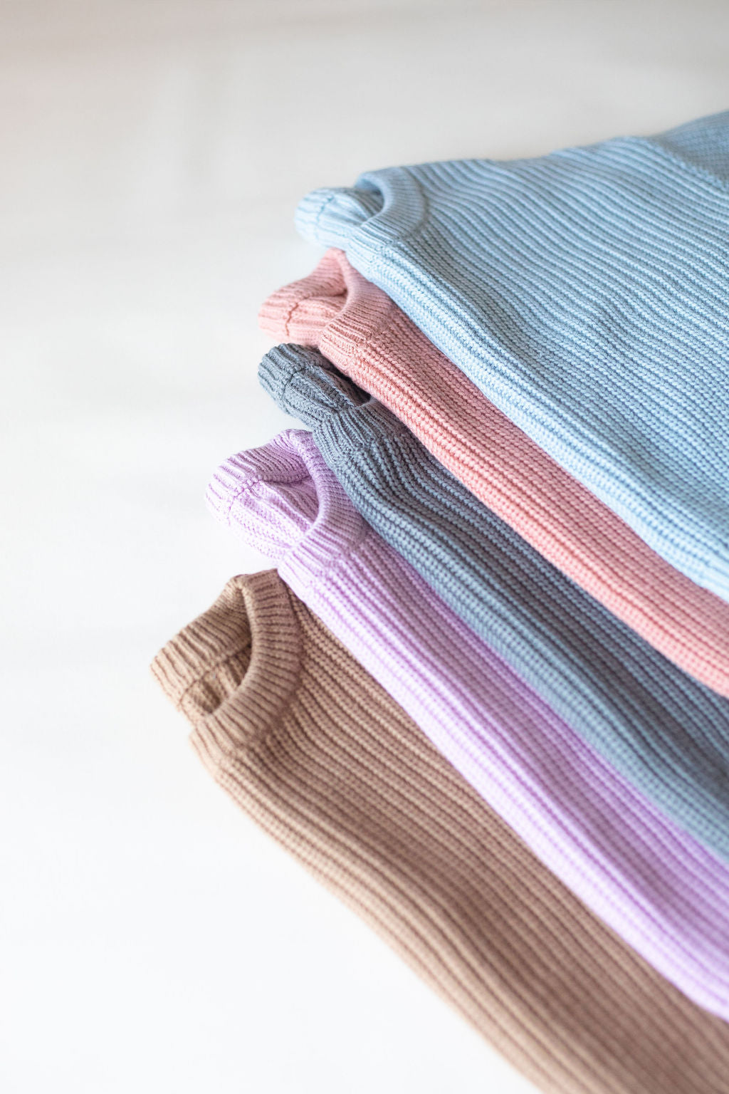 Stack of folded ribbed knit fabric in pastel colors on a white background