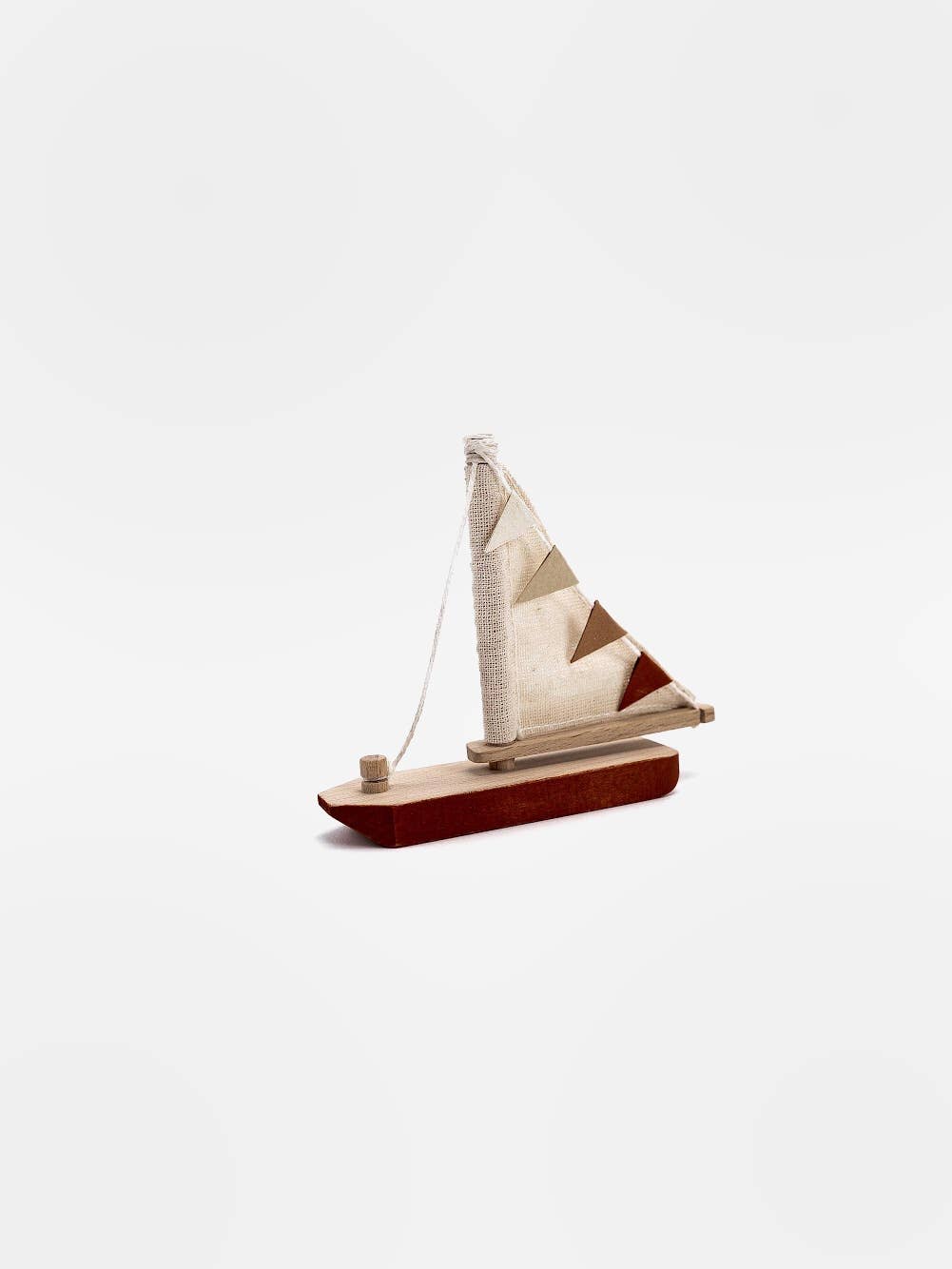 Wooden toy boat with pennant flag on the sail and a red bottom on a while back ground