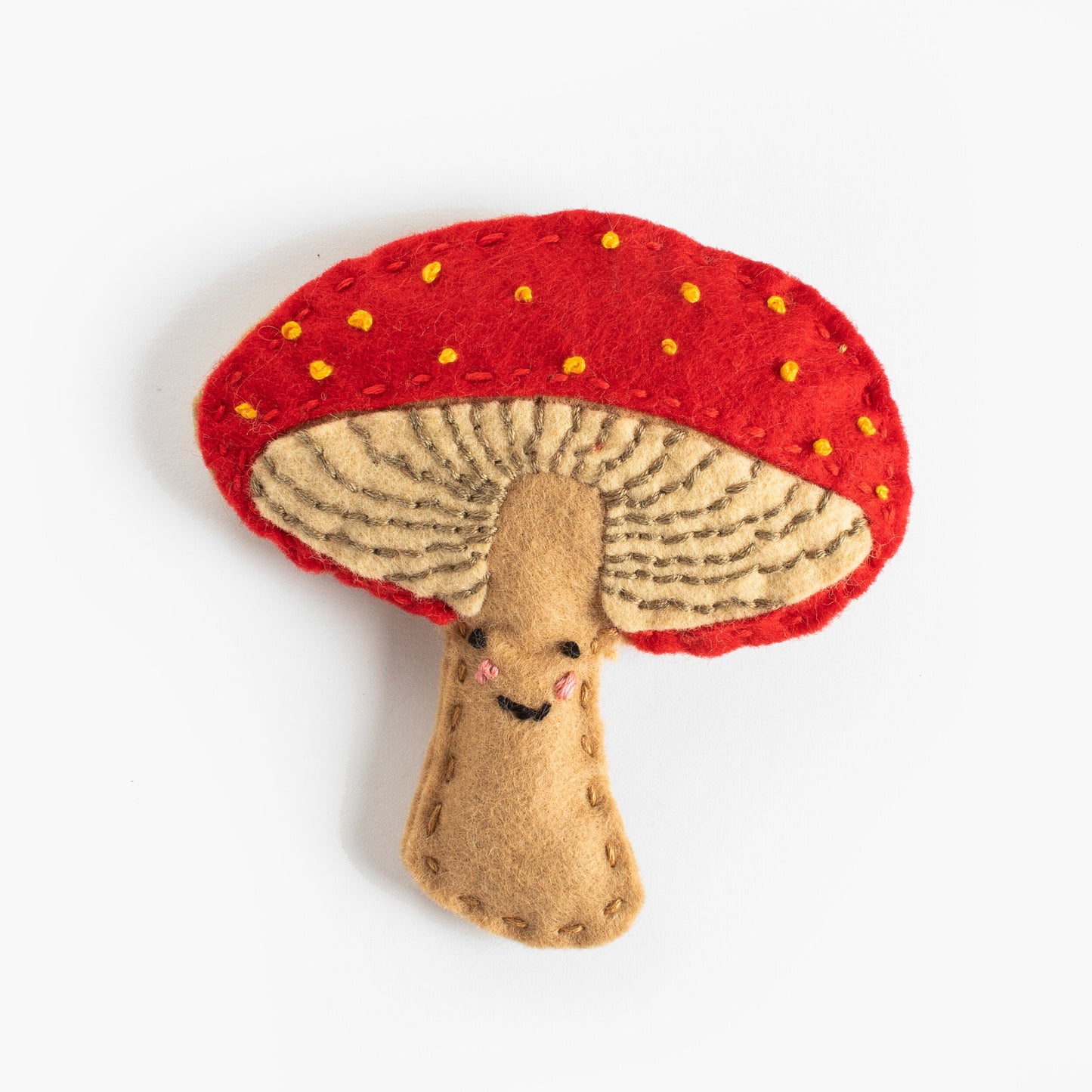 Felt mushroom toy with a red cap and beige stem on a white background