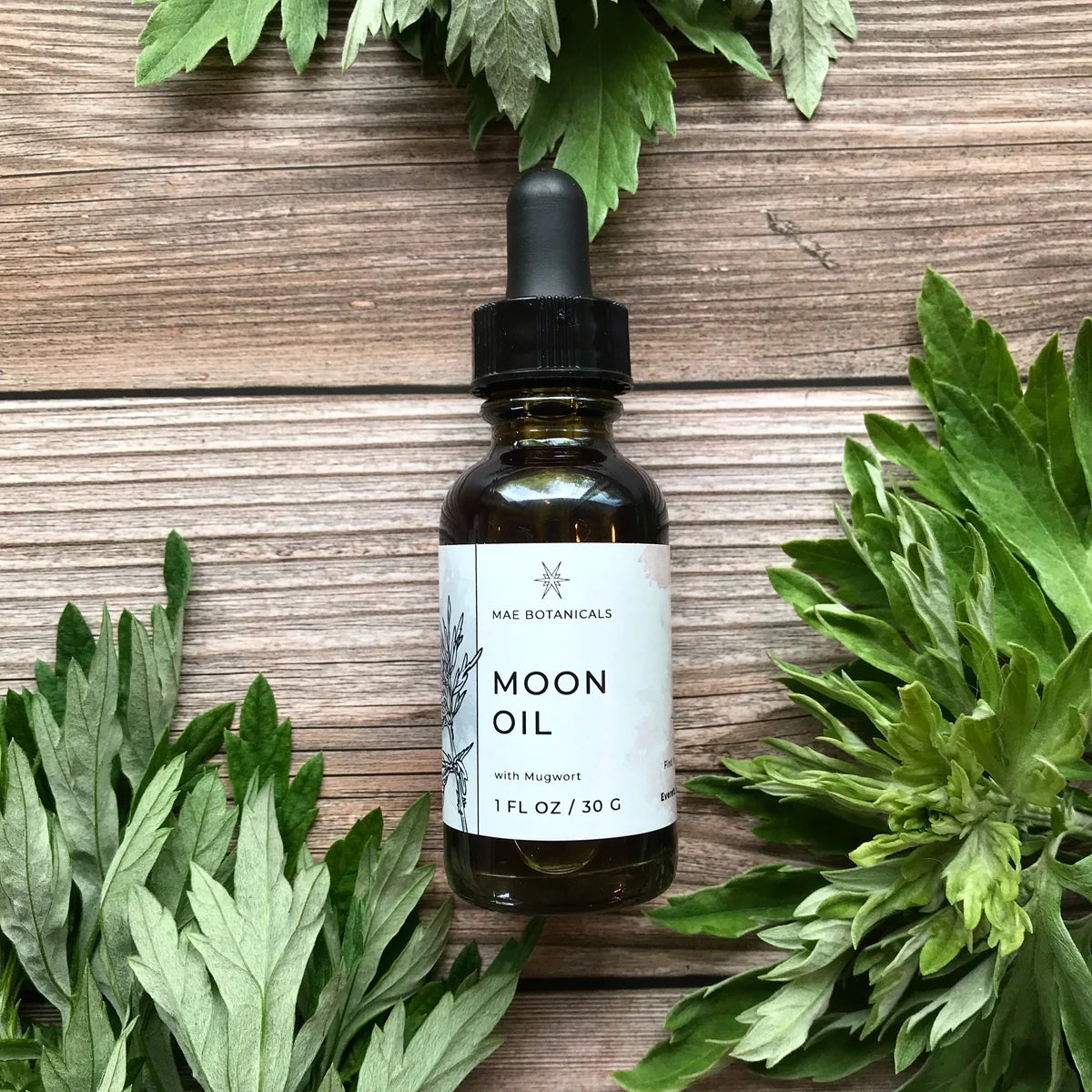 1oz bottle of Moon Oil on a wooden table with leaves