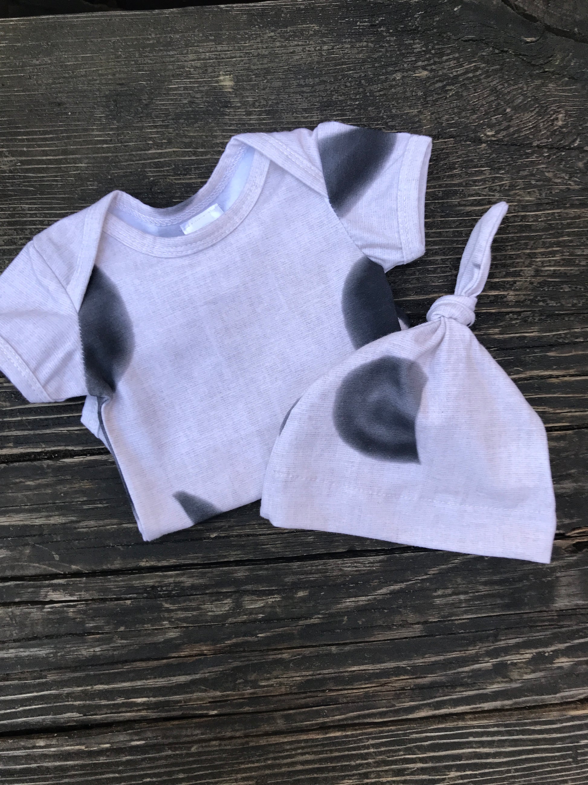 Short sleeve moon phase onesie with hat  on a wood bench