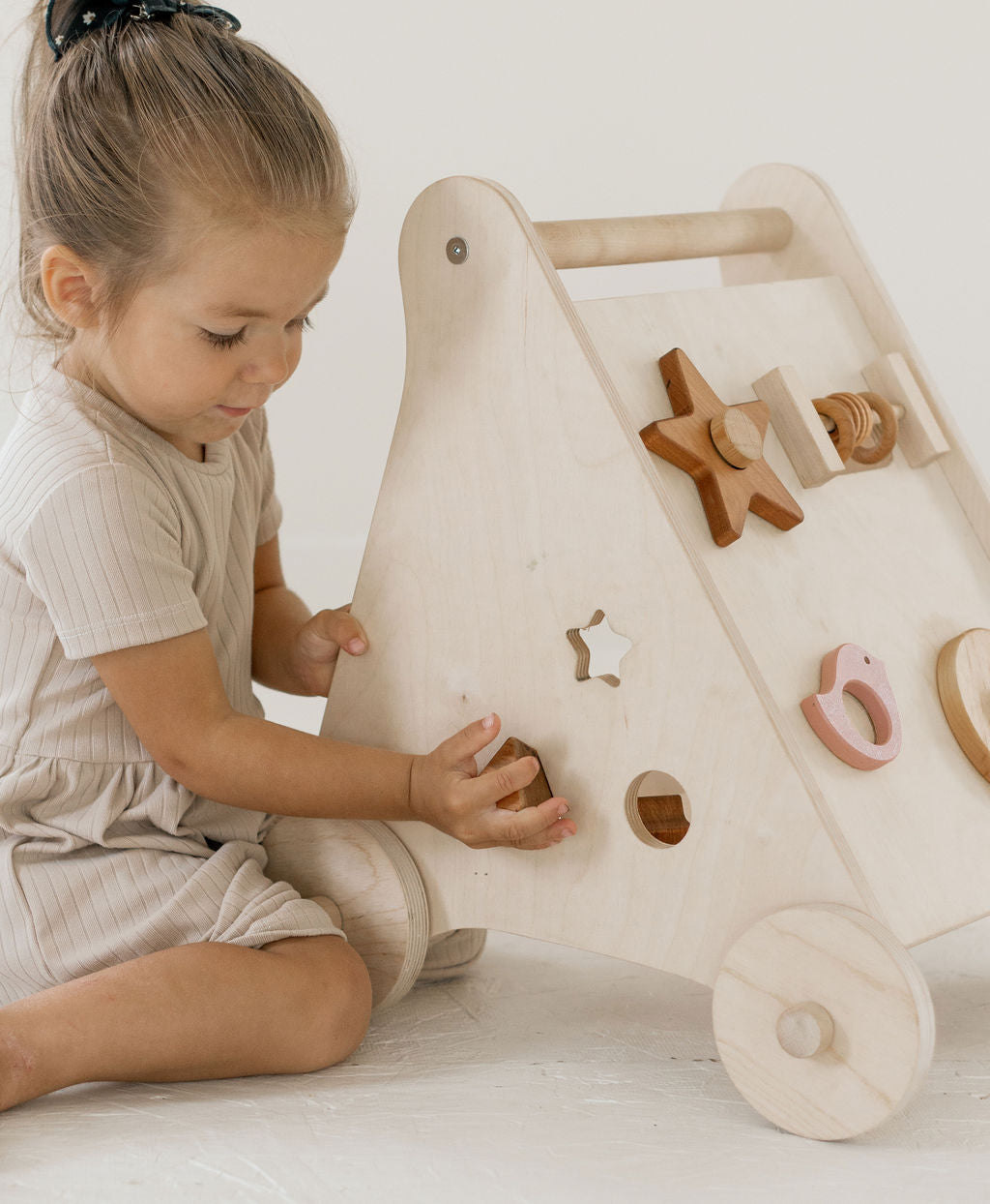 Child playing with a wooden toy shaped like a tree with various wooden shapes.