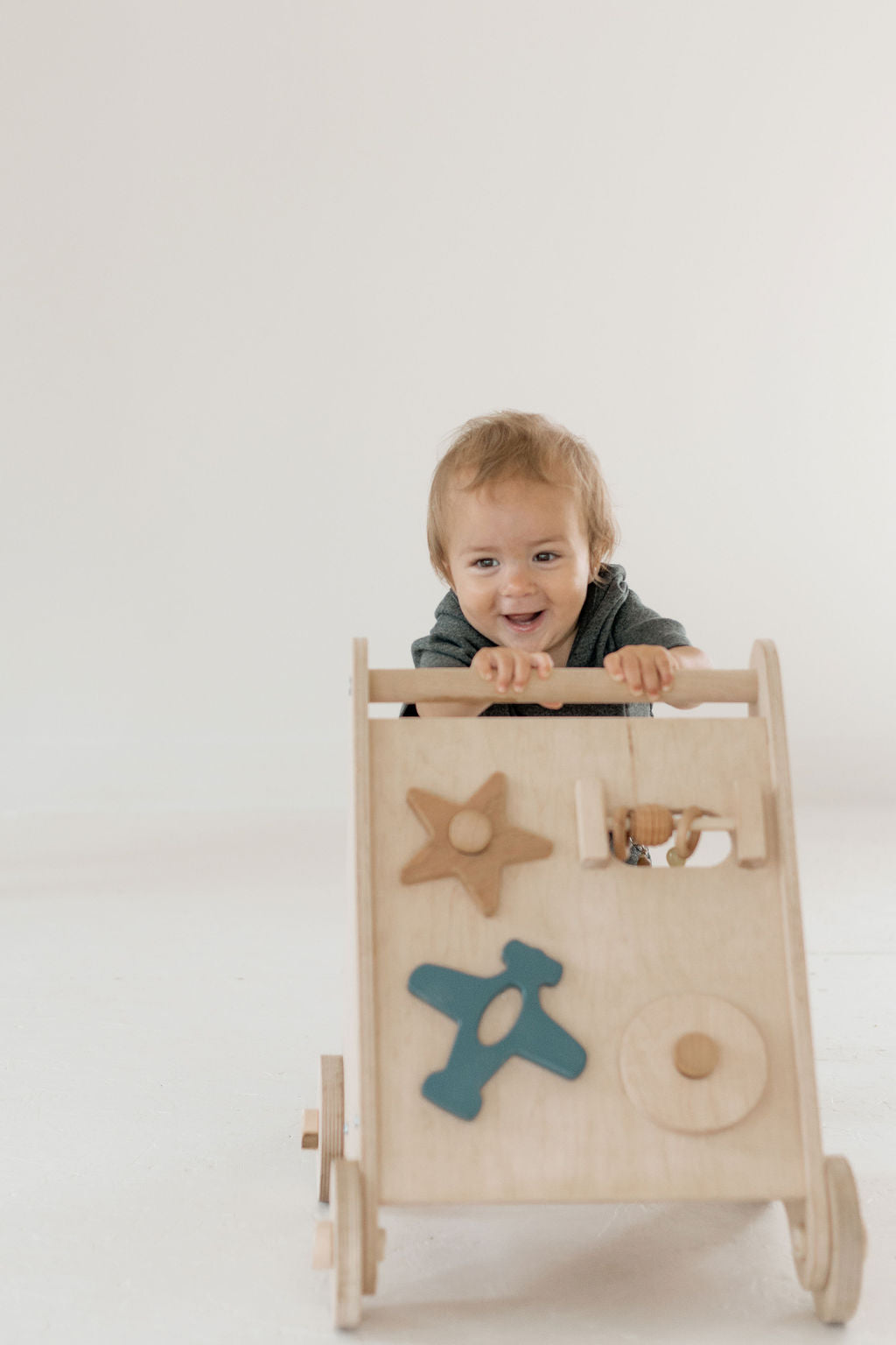 Child playing with a wooden toy cart on a white background