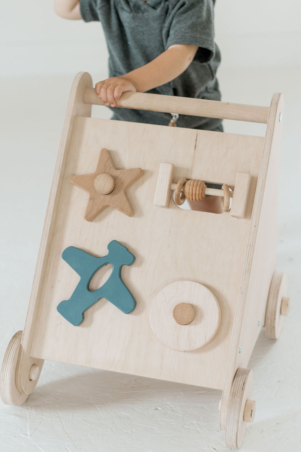 Wooden toy with shapes and a child holding it on a light background
