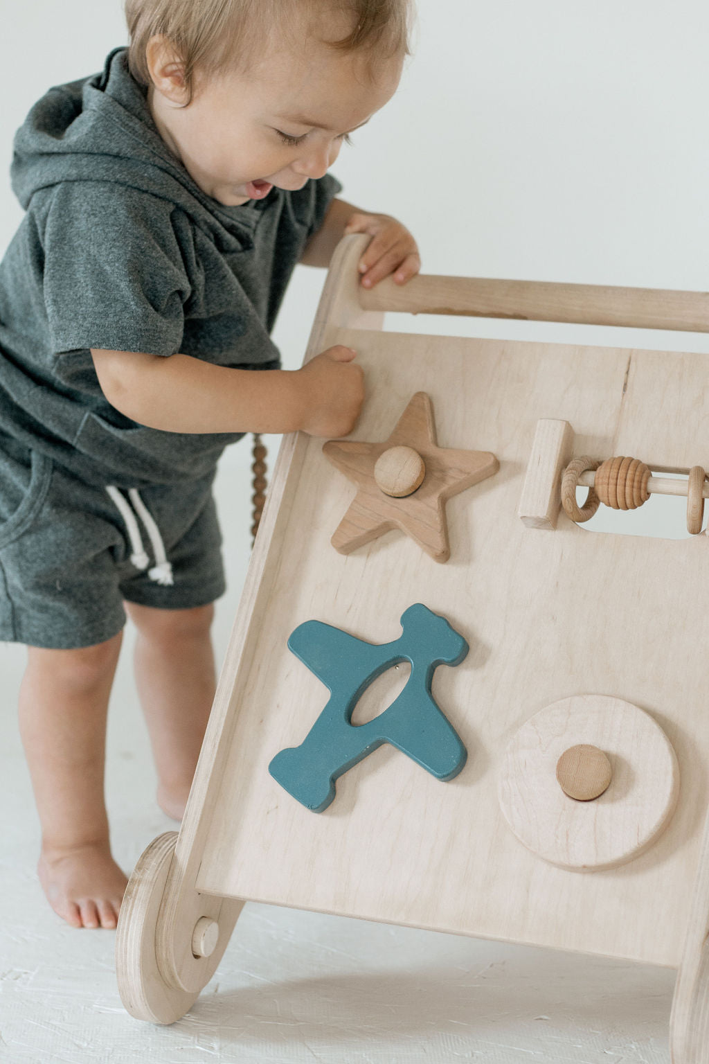 Child playing with a wooden activity board featuring shapes and textures.