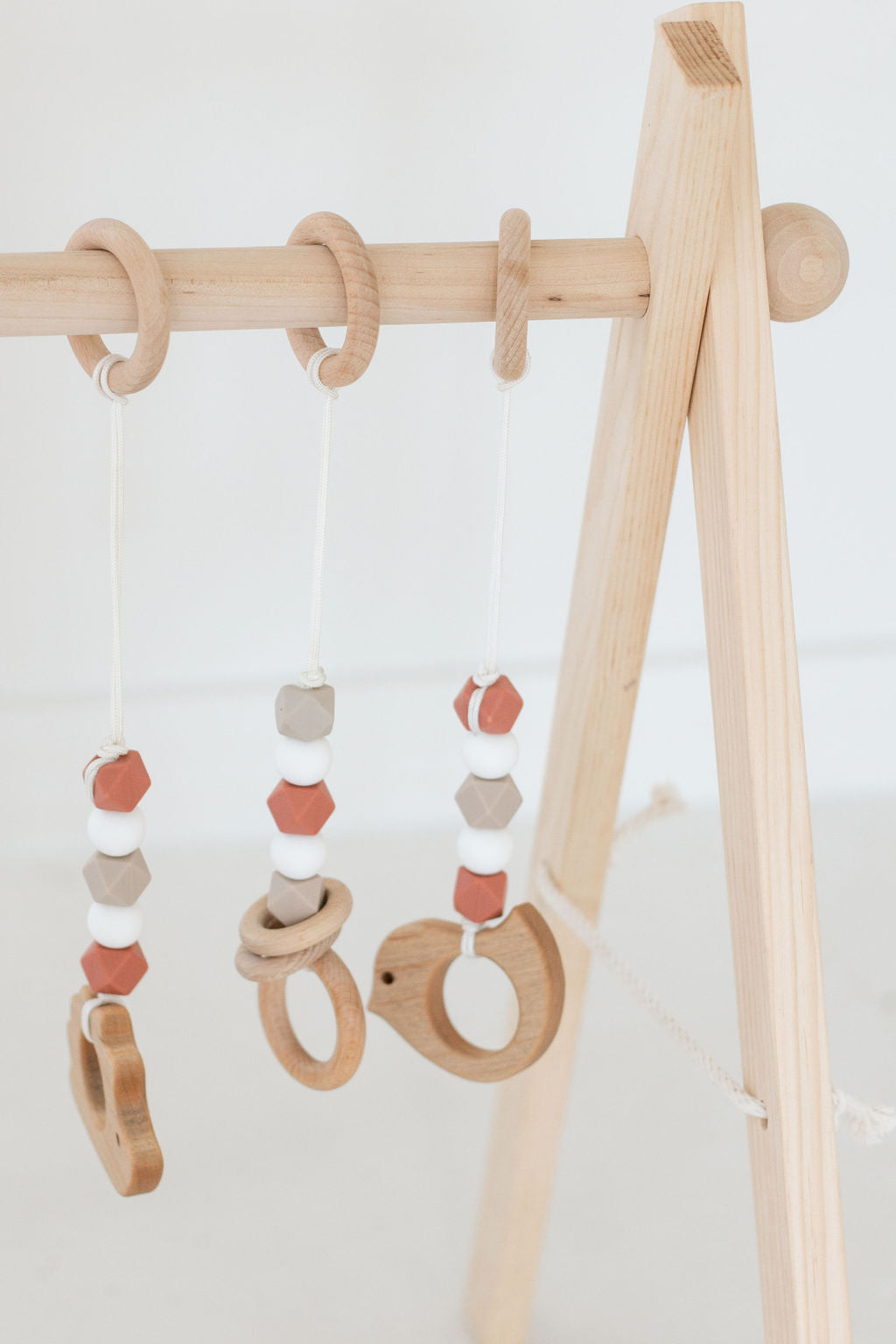 Wooden baby teething rings on a wooden stand against a white background