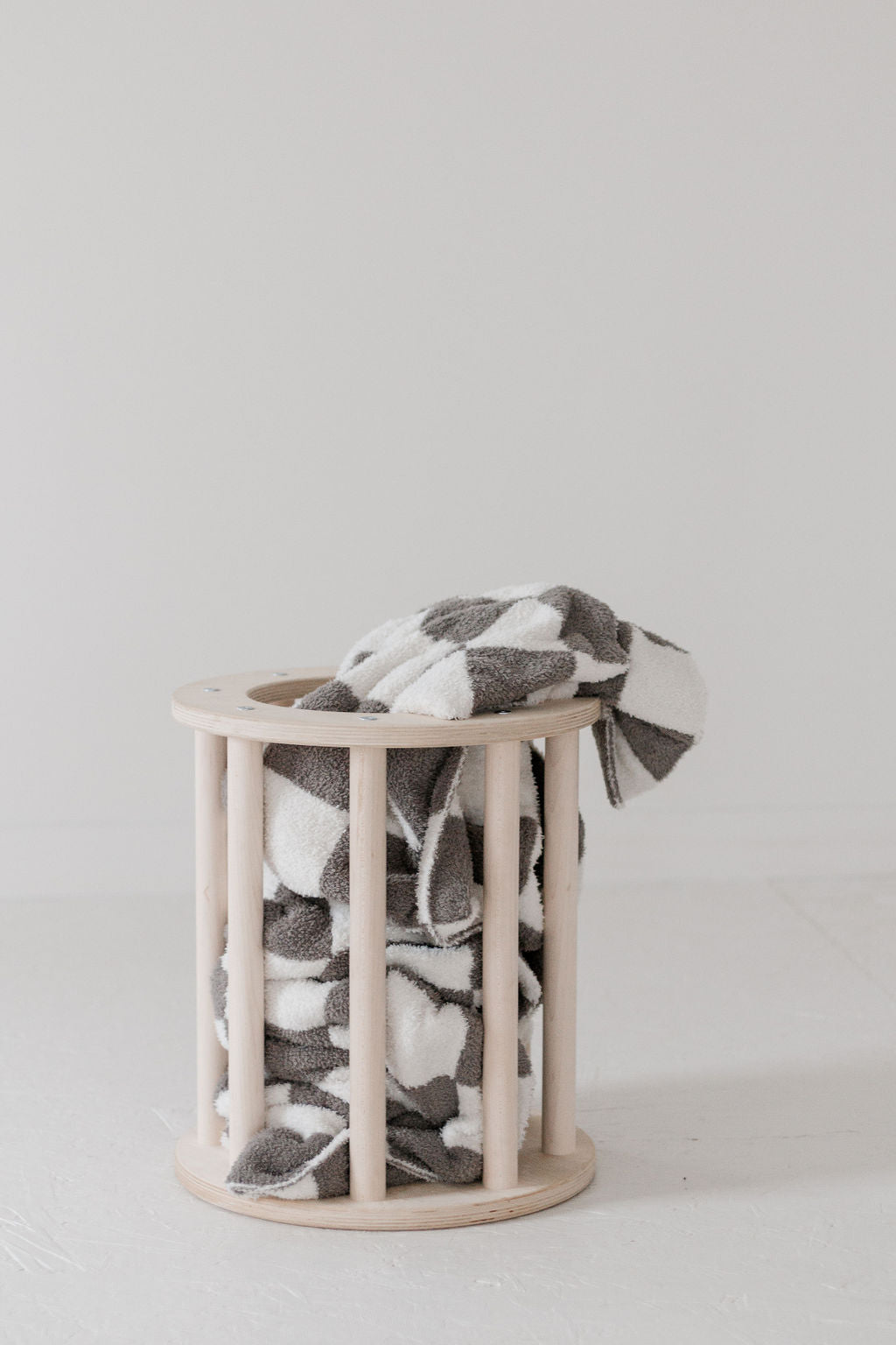 Patterned blanket draped over a wooden basket on a light background