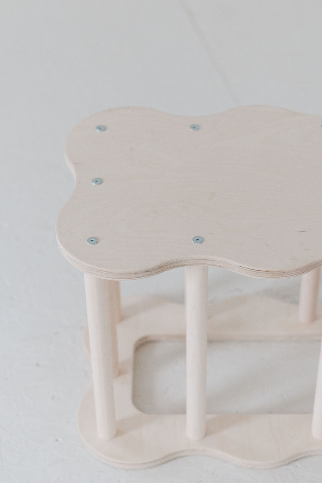 Small, light-colored wooden stool on a white background