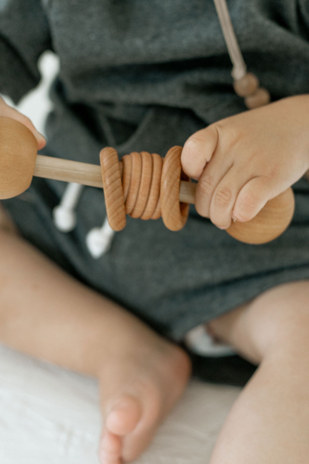 Child's hands holding a wooden rattle