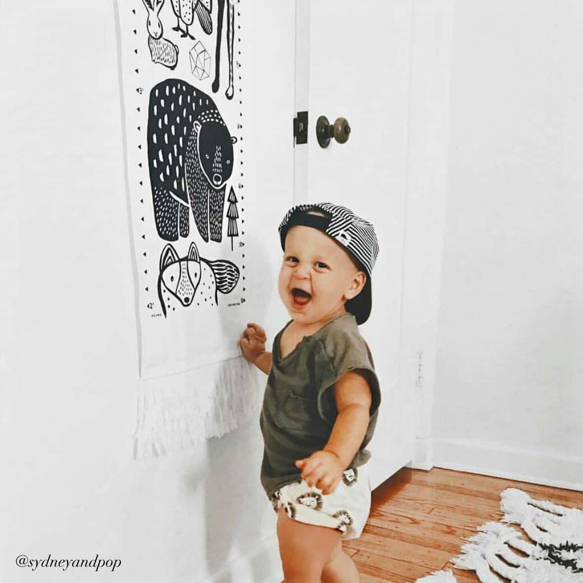 Child in a room with a decorative wall hanging featuring animal illustrations.