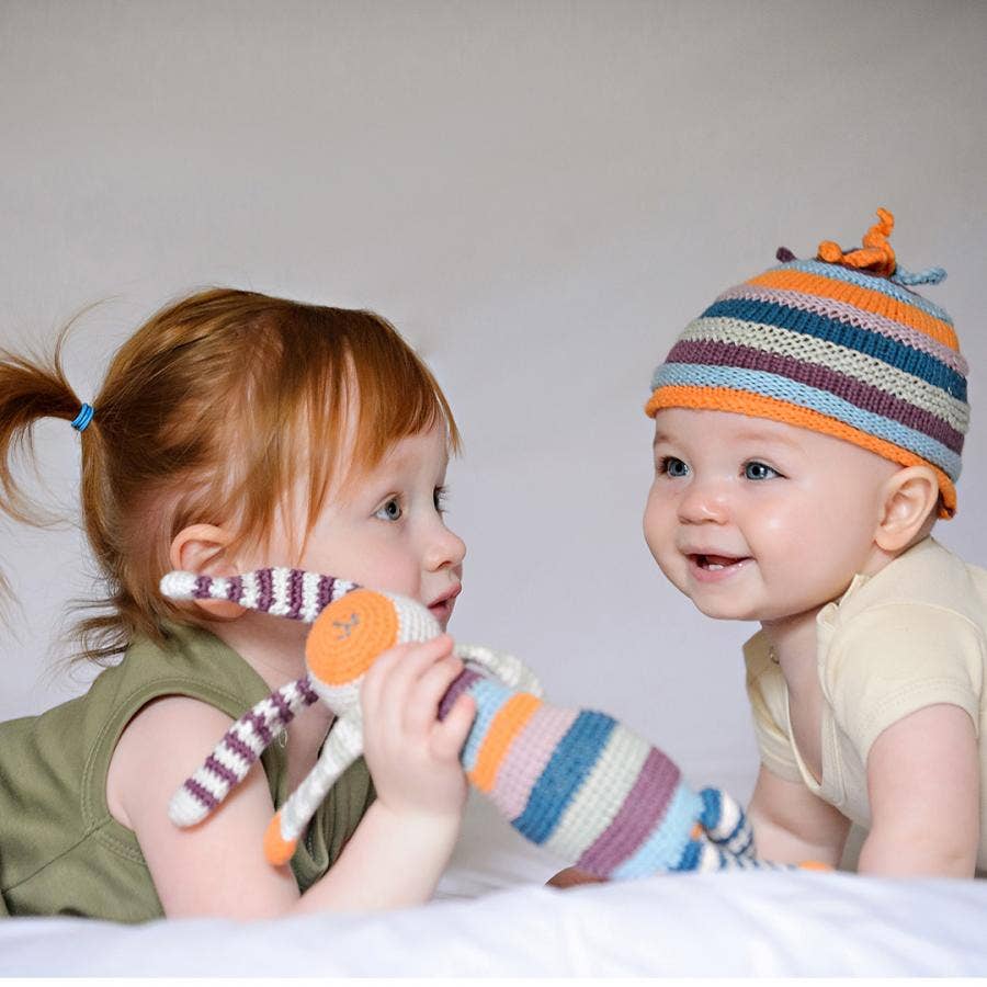 Two children playing with a colorful toy against a plain background