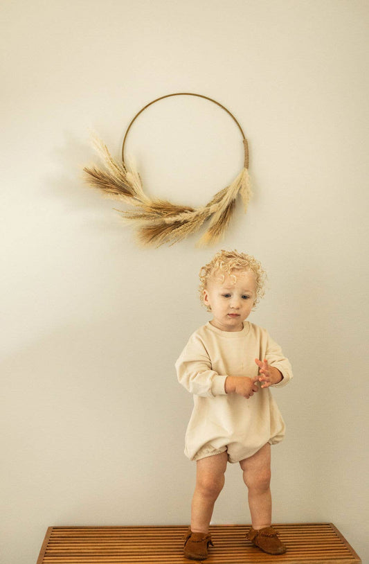 Child standing on a wooden step with a decorative wreath on a wall