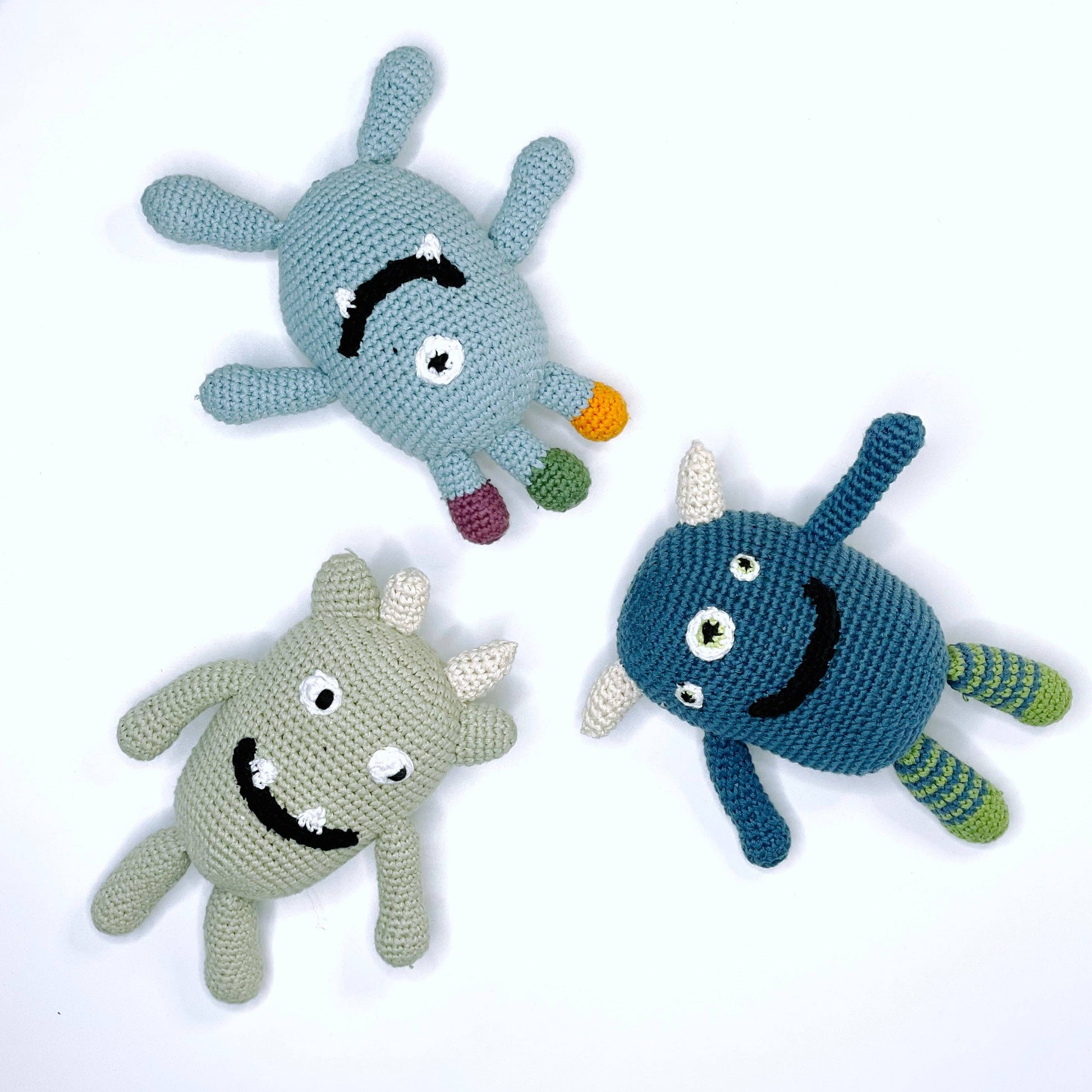 Three crocheted toy monsters on a white background