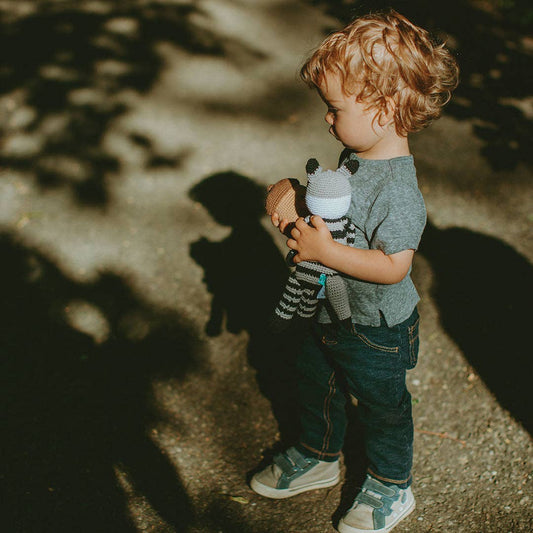 Child holding a stuffed animal in a park setting