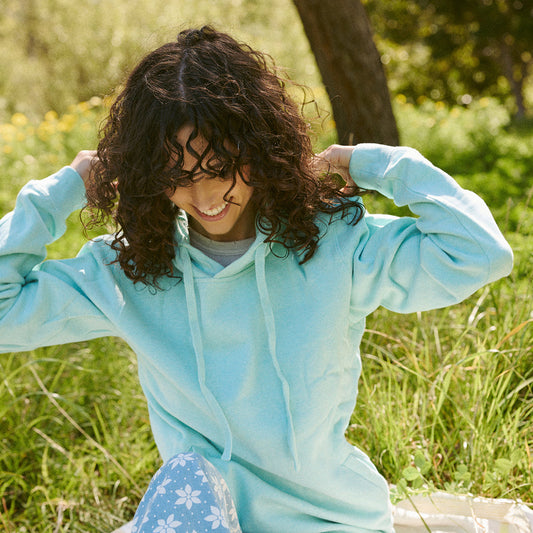 Woman in a light blue hoodie sitting in a grassy field