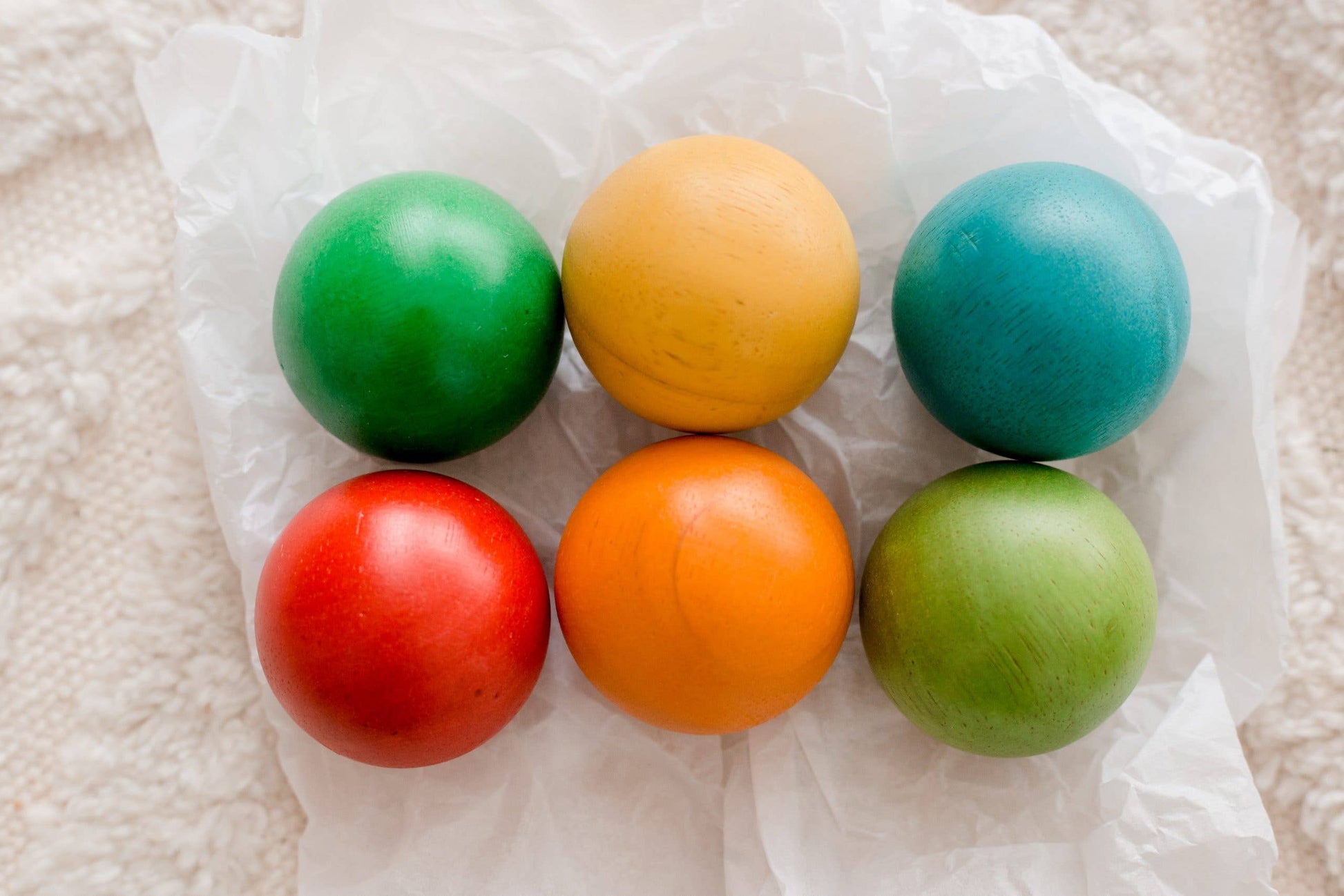 Six colorful wooden balls on a white fabric background