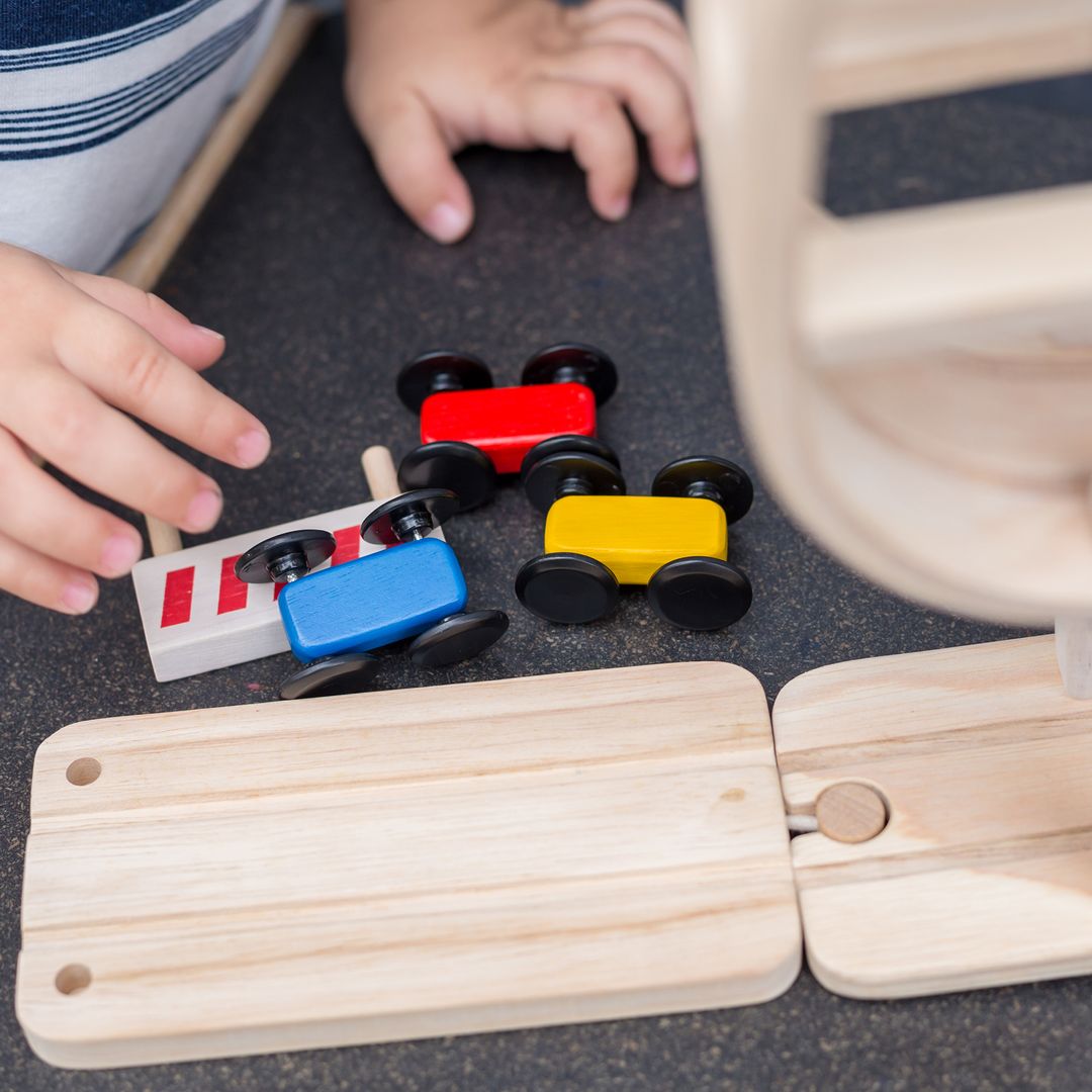 Children playing with wooden toy cars on a track