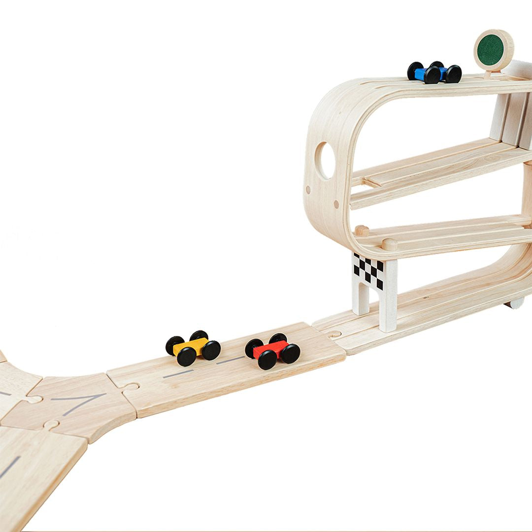Wooden toy track with cars and a small car house on a white background