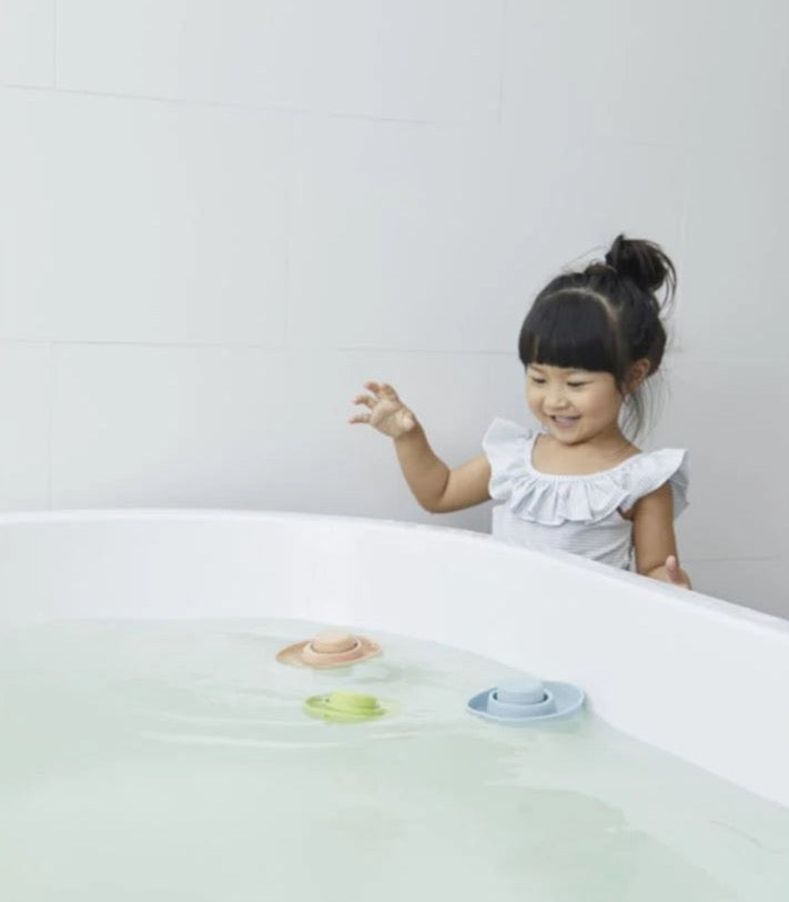 Child playing with natural rubber convertible boats in a bathtub