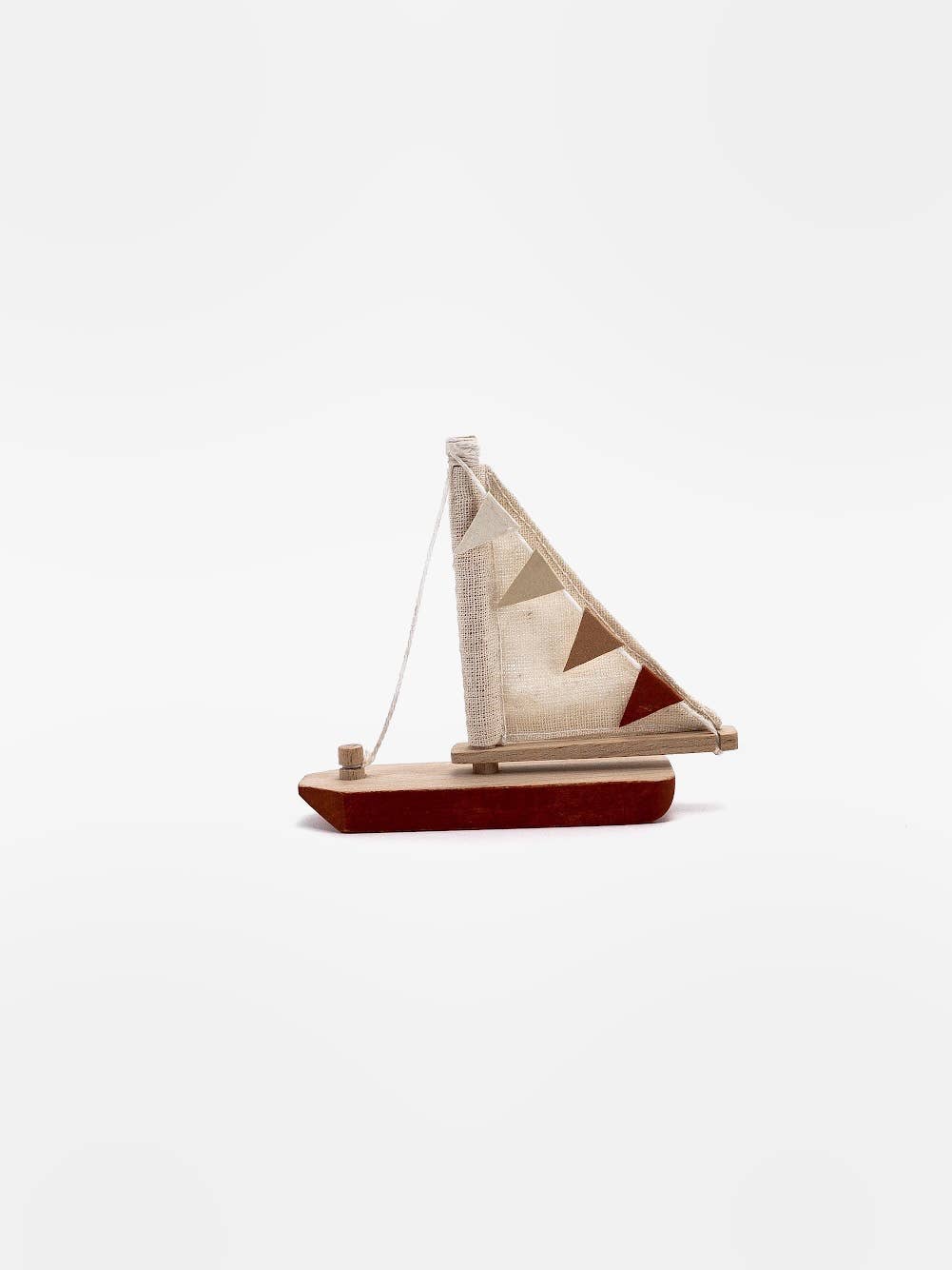 Wooden toy boat with pennant flag on the sail and a red bottom on a while back ground