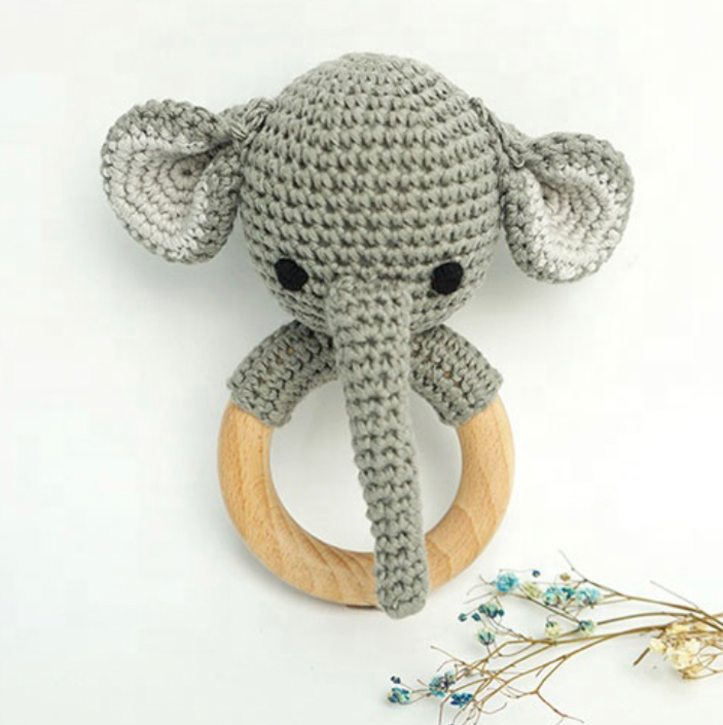 Crocheted elephant rattle with wooden ring on a white background
