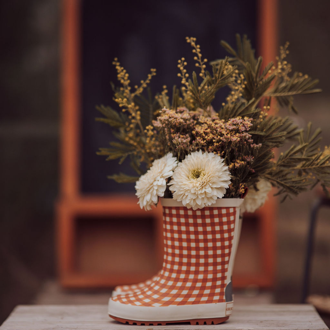 Checkered boot filled with flowers on a wooden surface