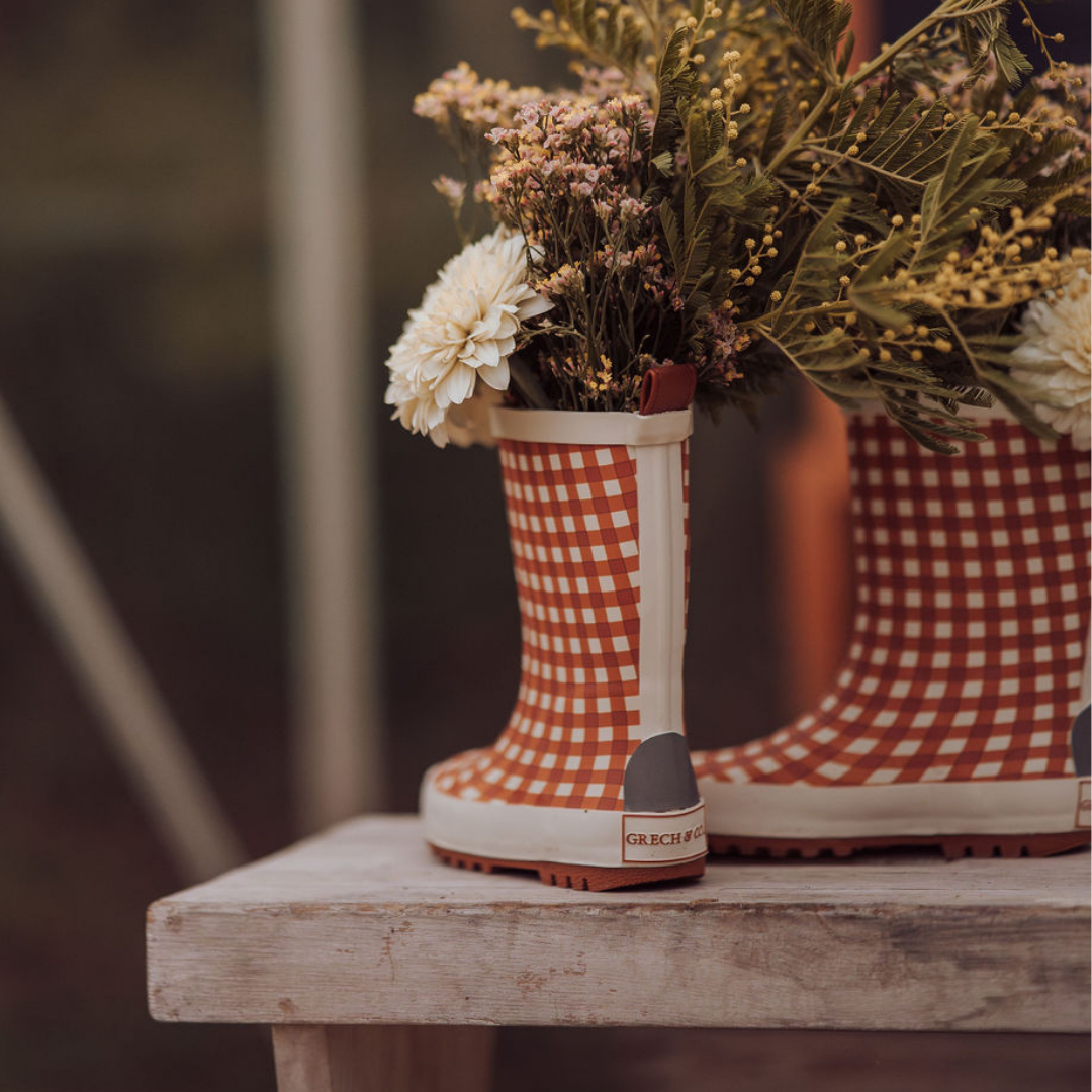 Red and white checkered boots with flowers inside on a wooden surface
