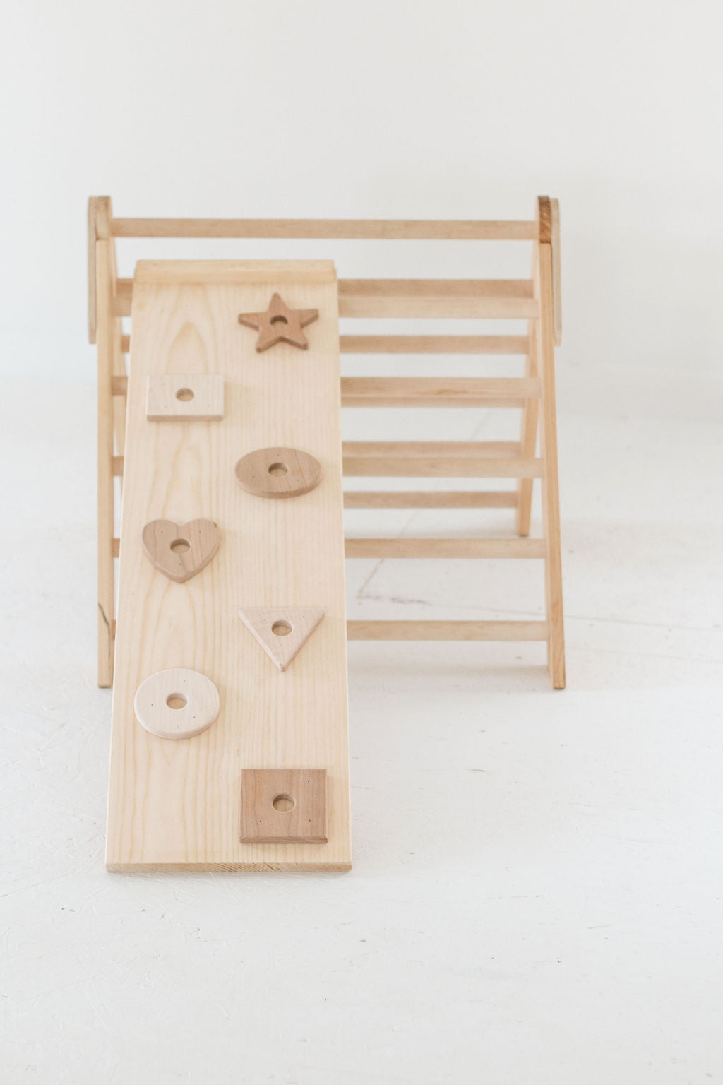 Wooden climbing toy with various shapes on a white background