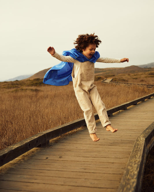 child jumping in the air wearing starry night play cape