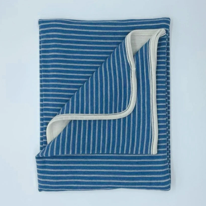 Folded blue and white striped blanket on a light blue background