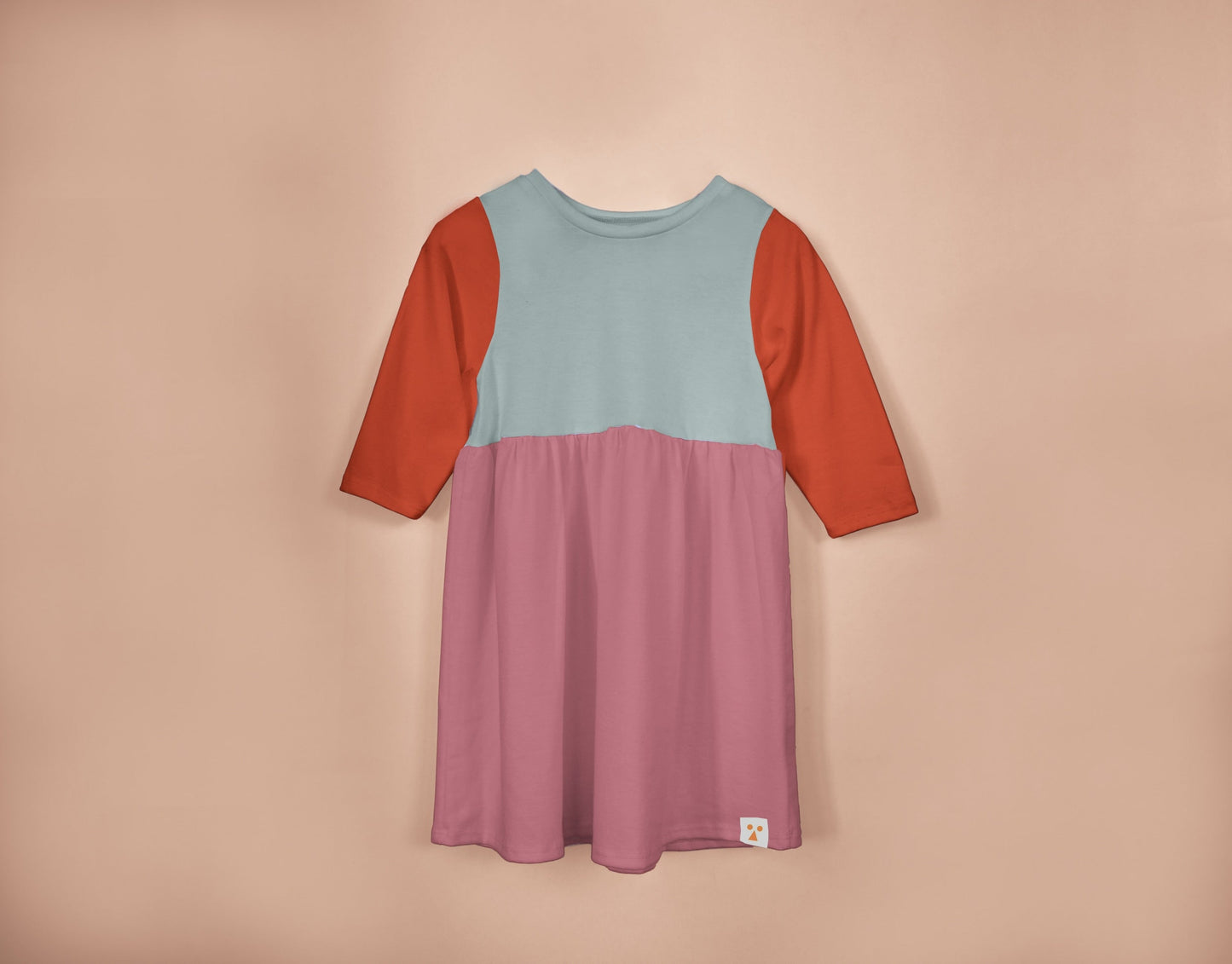 Three-color dress with red sleeves and pink bottom on a beige background