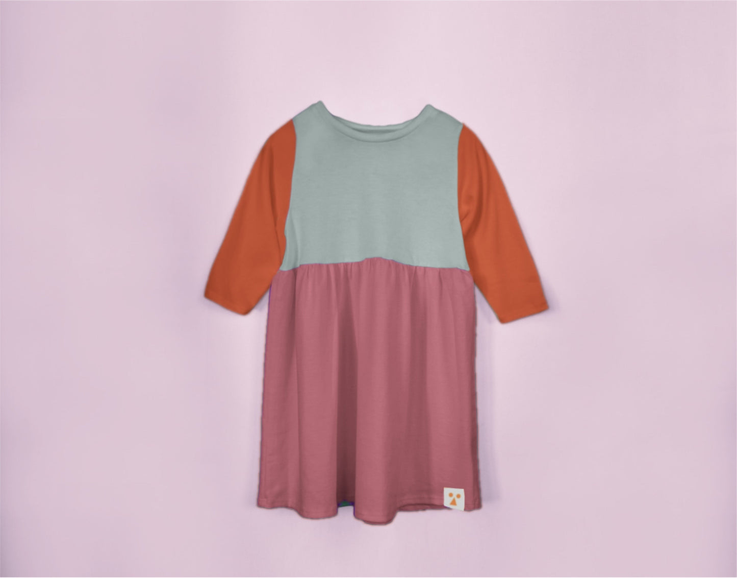 Color-blocked dress with green, orange, and pink sections on a light purple background