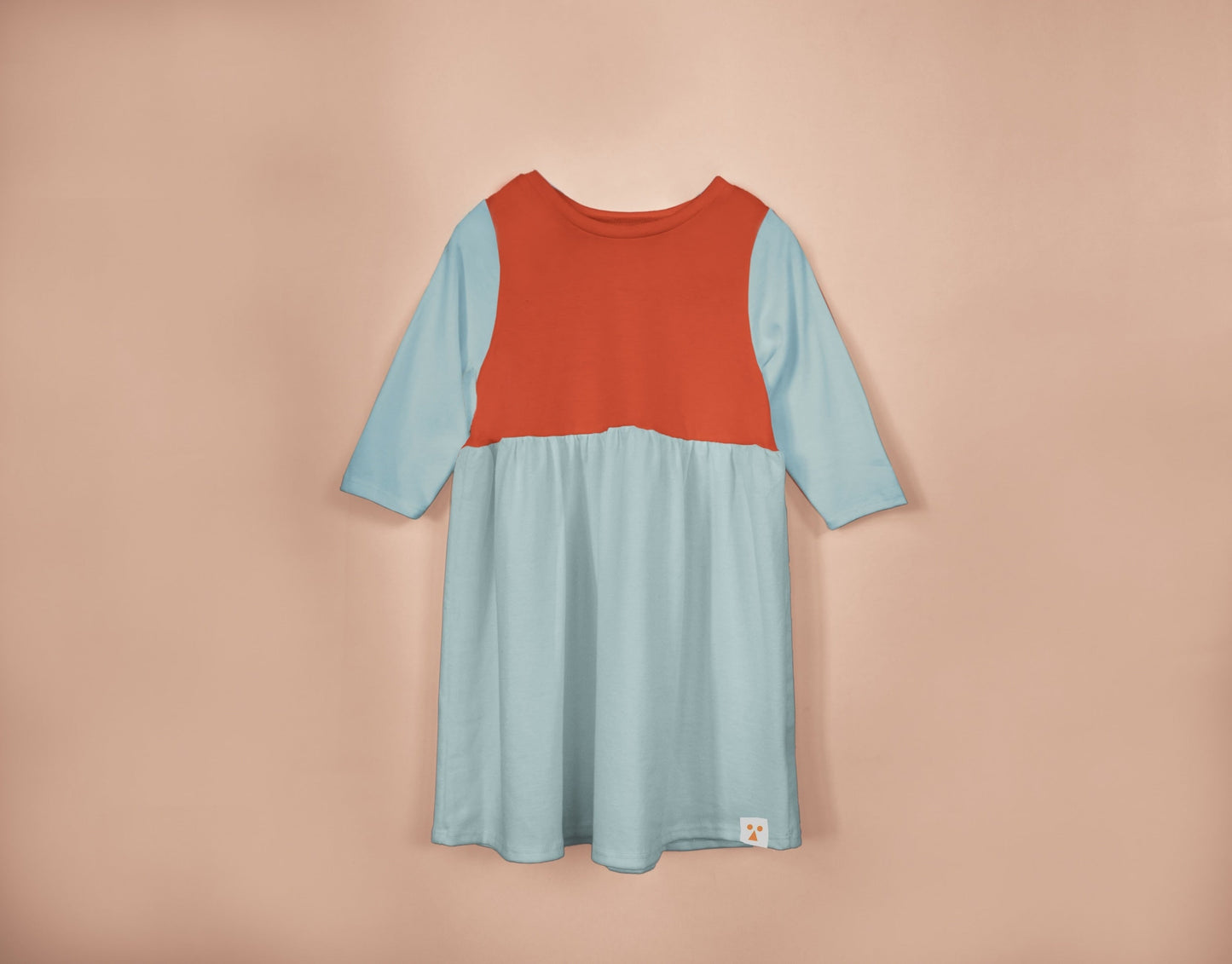 Two-tone dress with red top and blue skirt on a beige background