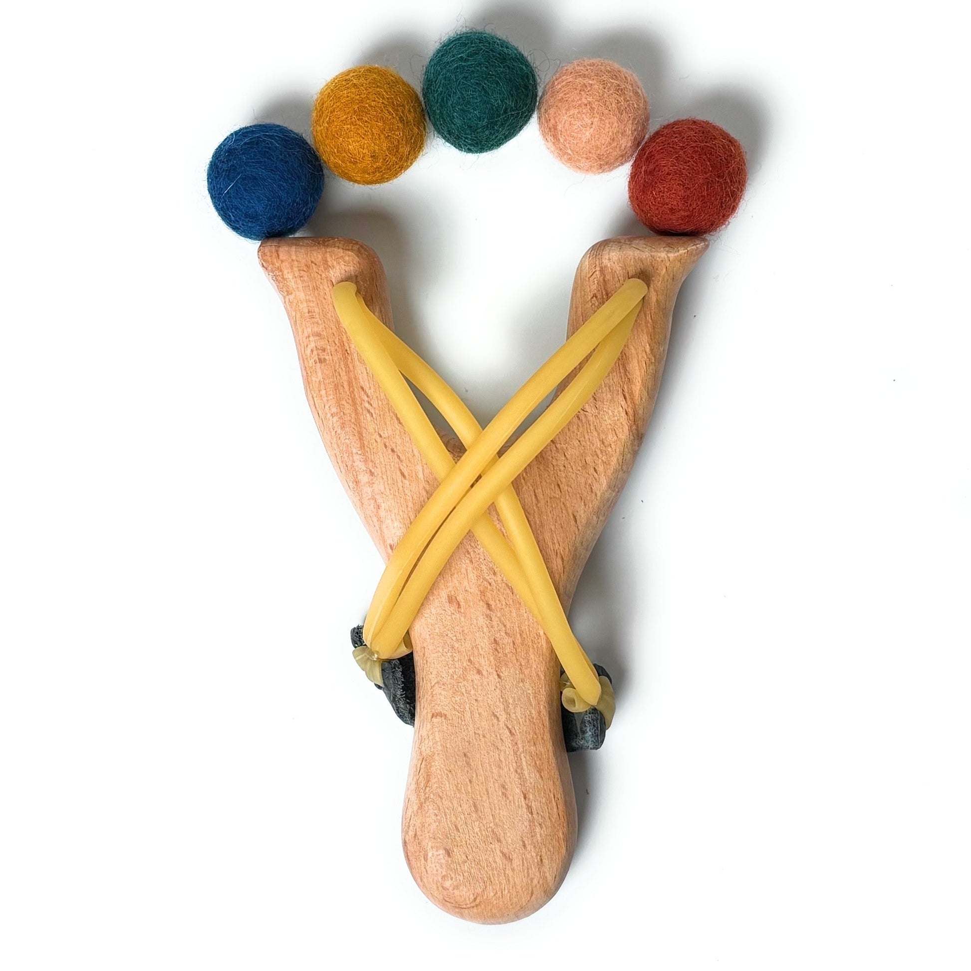 Wooden slingshot with colorful balls on a white background