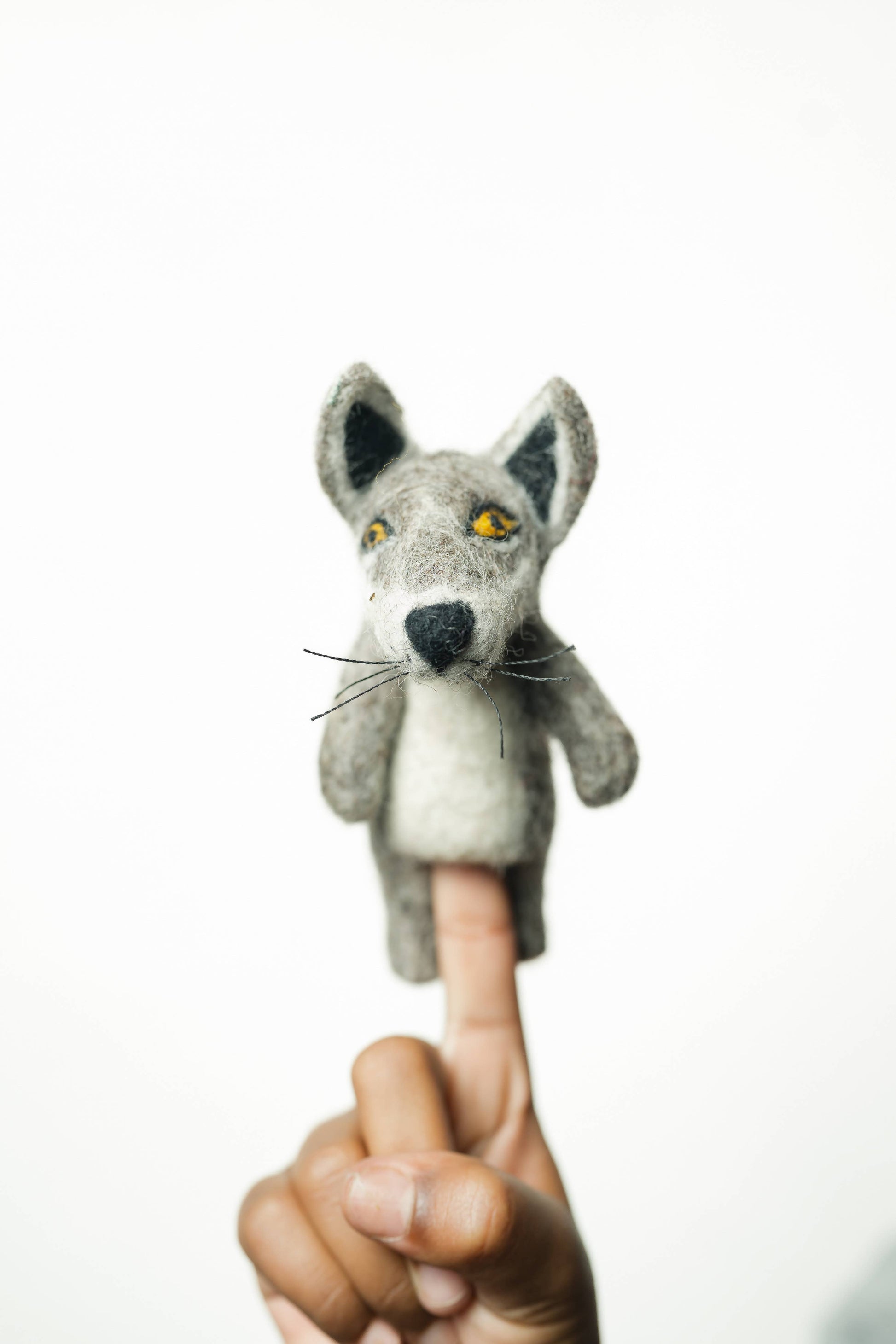 Gray fox finger puppet on a person's index finger against a white background