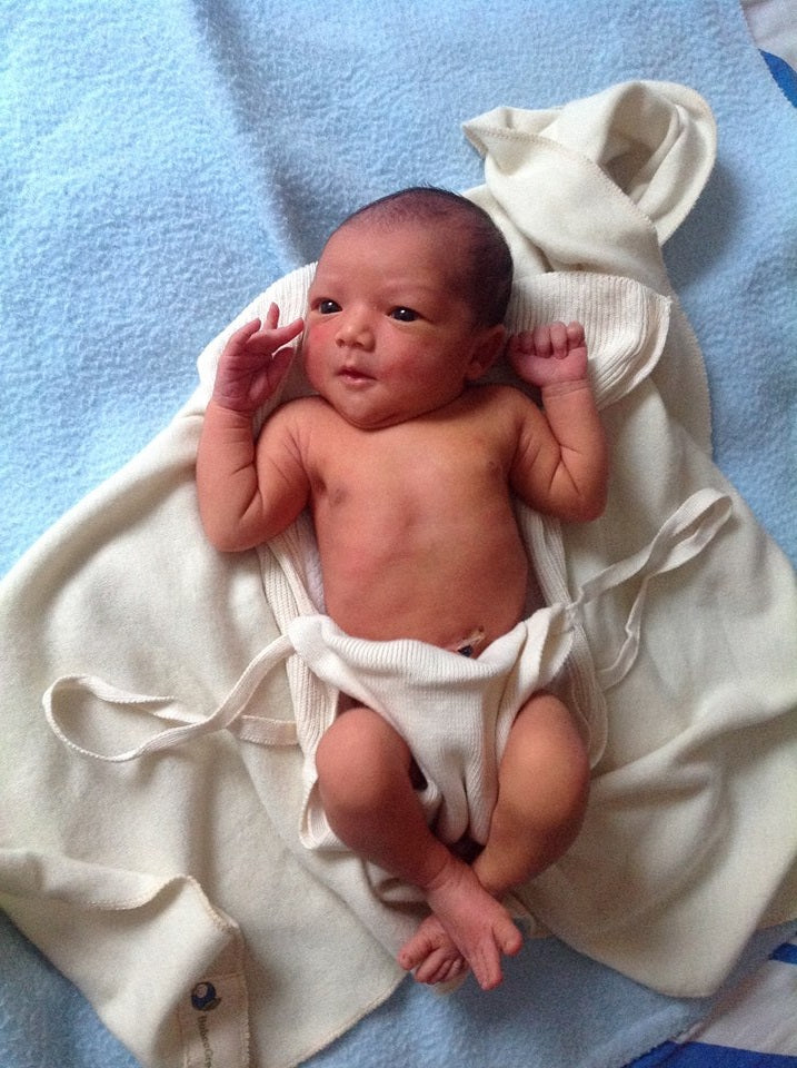 Newborn baby lying on a white blanket with a blue background