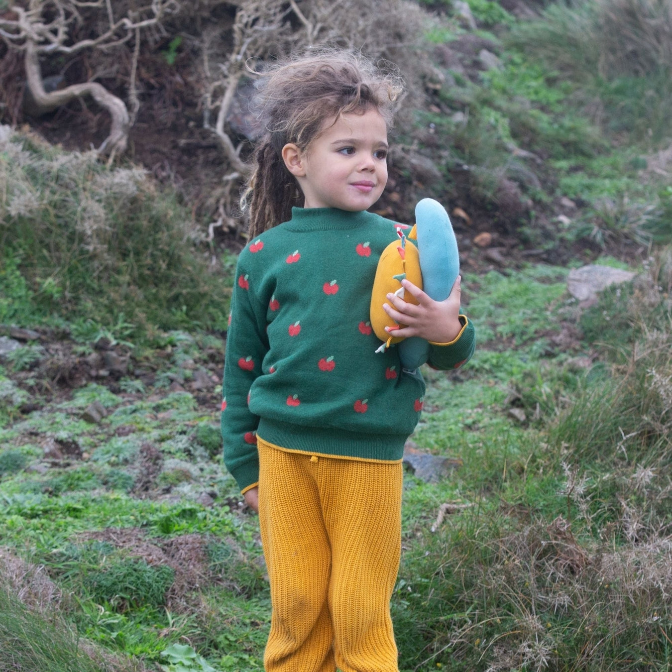 Child out side wearing an apple sweater