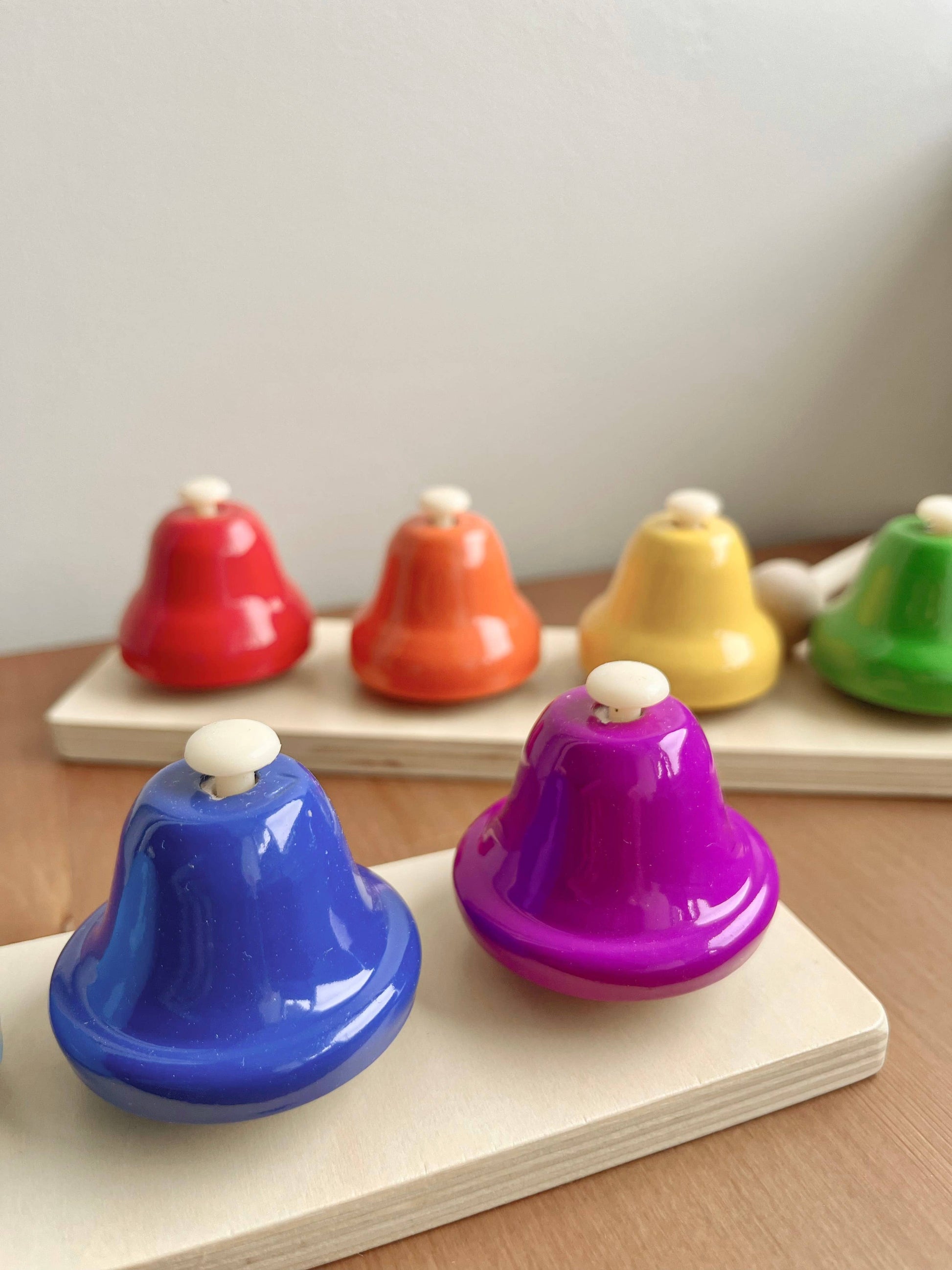 Colorful bells on a wooden surface with a neutral background