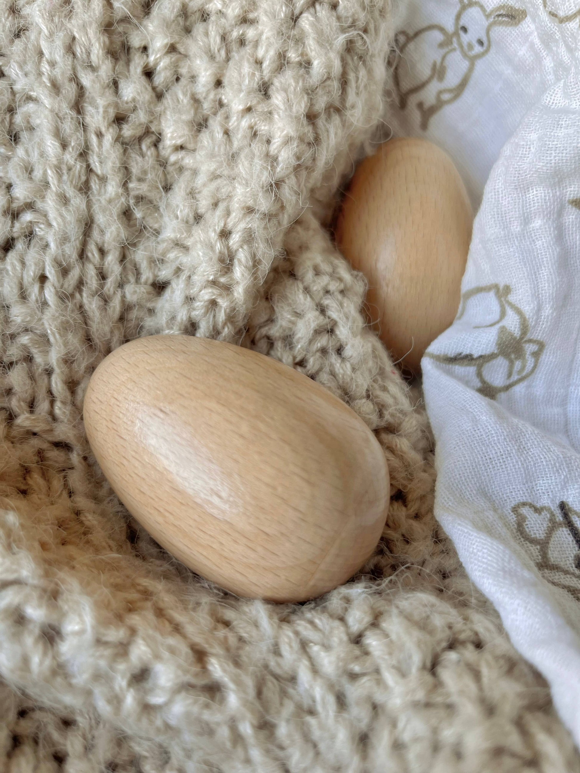 Two wooden egg shakers on a knitted blanket