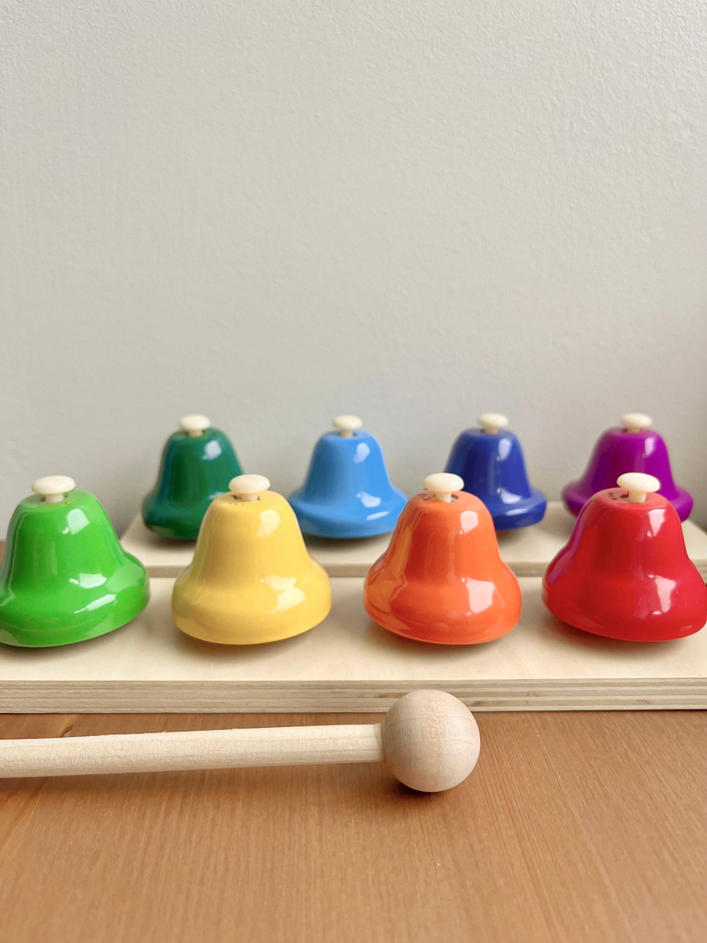Colorful wooden bells with a mallet on a wooden surface