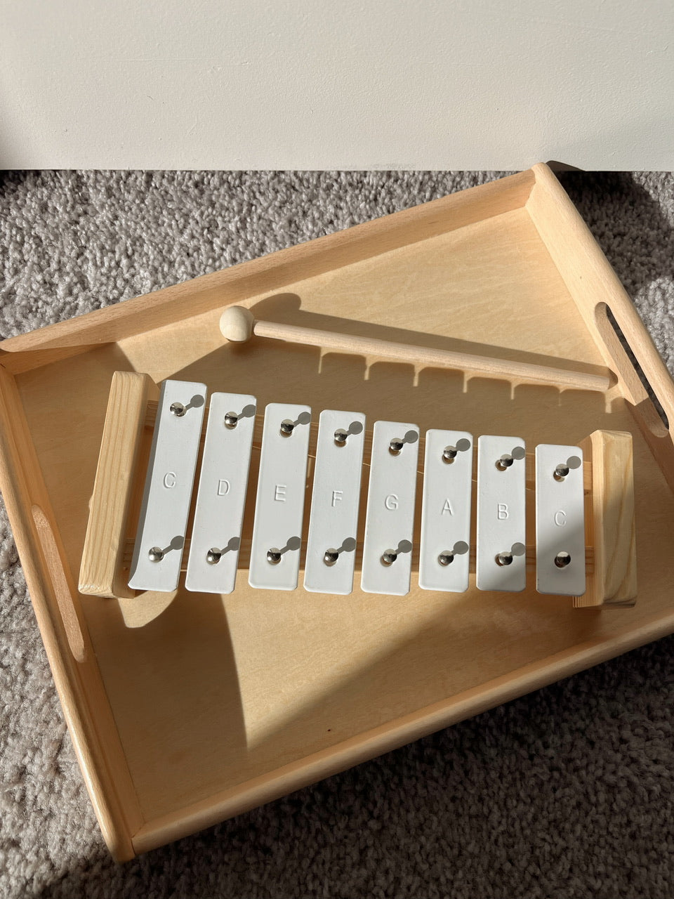 Wooden xylophone with metal keys on a carpeted floor