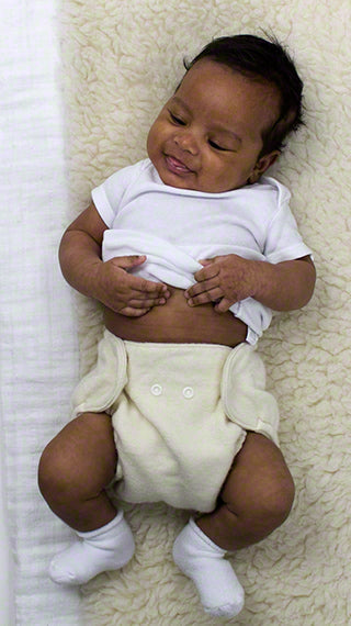 Baby wearing a white shirt and cream-colored diaper on a textured white surface