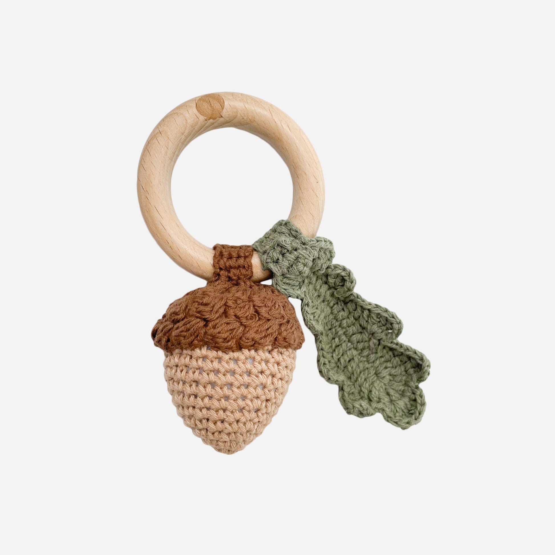 Wooden teething ring with knitted acorn and leaf on a white background
