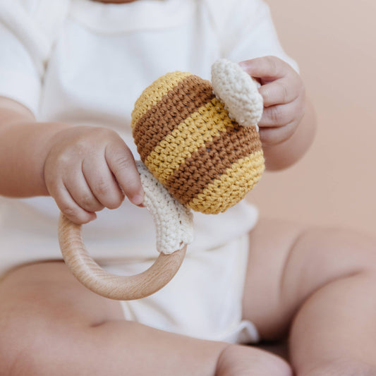 Baby holding a bee knitted rattle toy